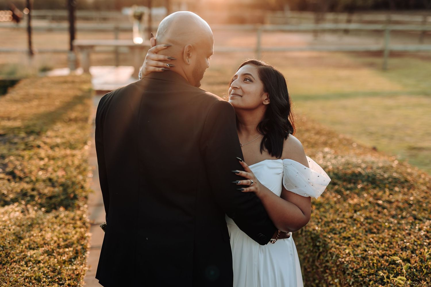 Romantic sunset wedding portrait showing tender moment between newlyweds in garden setting.