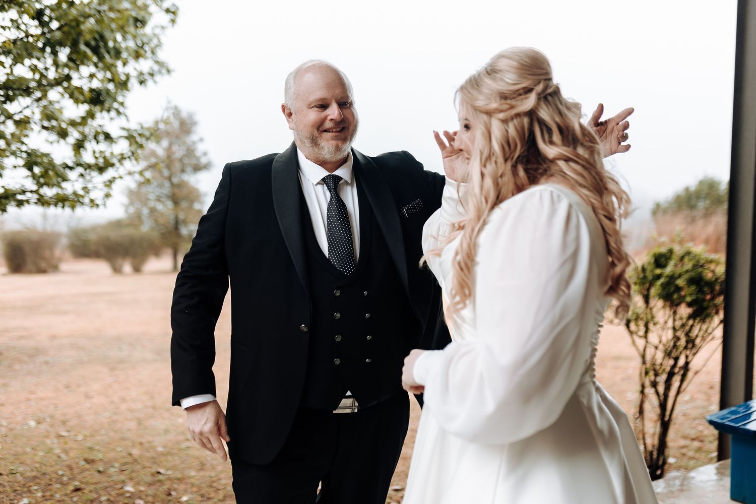 Candid outdoor wedding photo of couple sharing an emotional first look moment.
