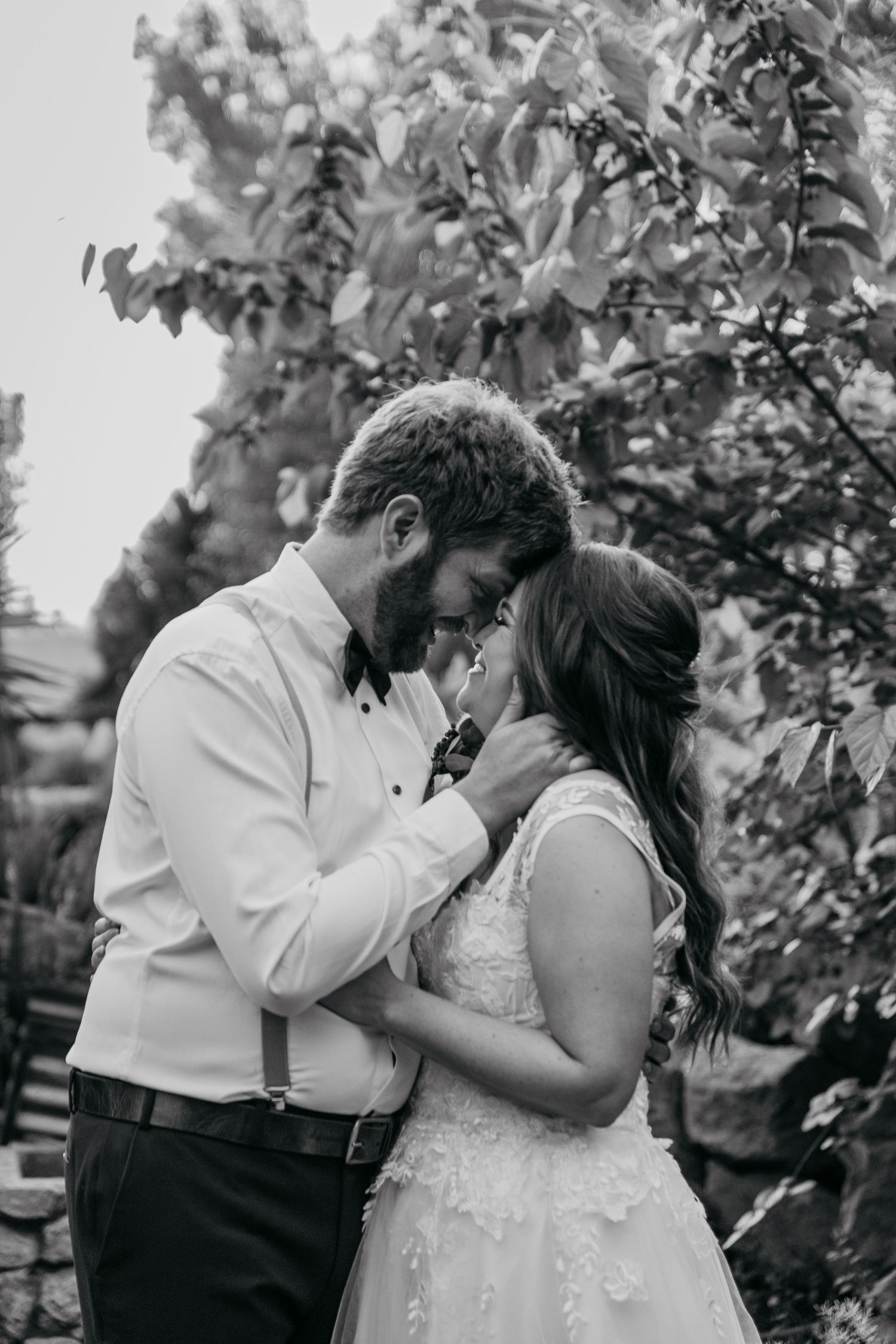 Intimate black and white portrait of couple sharing tender moment outdoors.