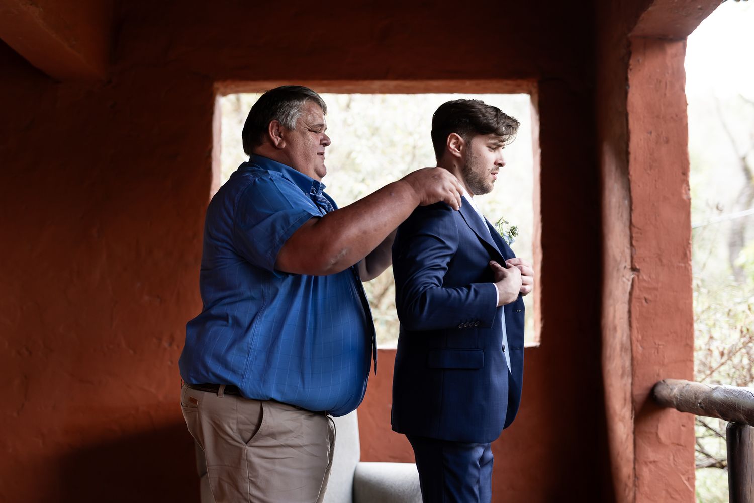 Helper making final adjustments to formal suit jacket.