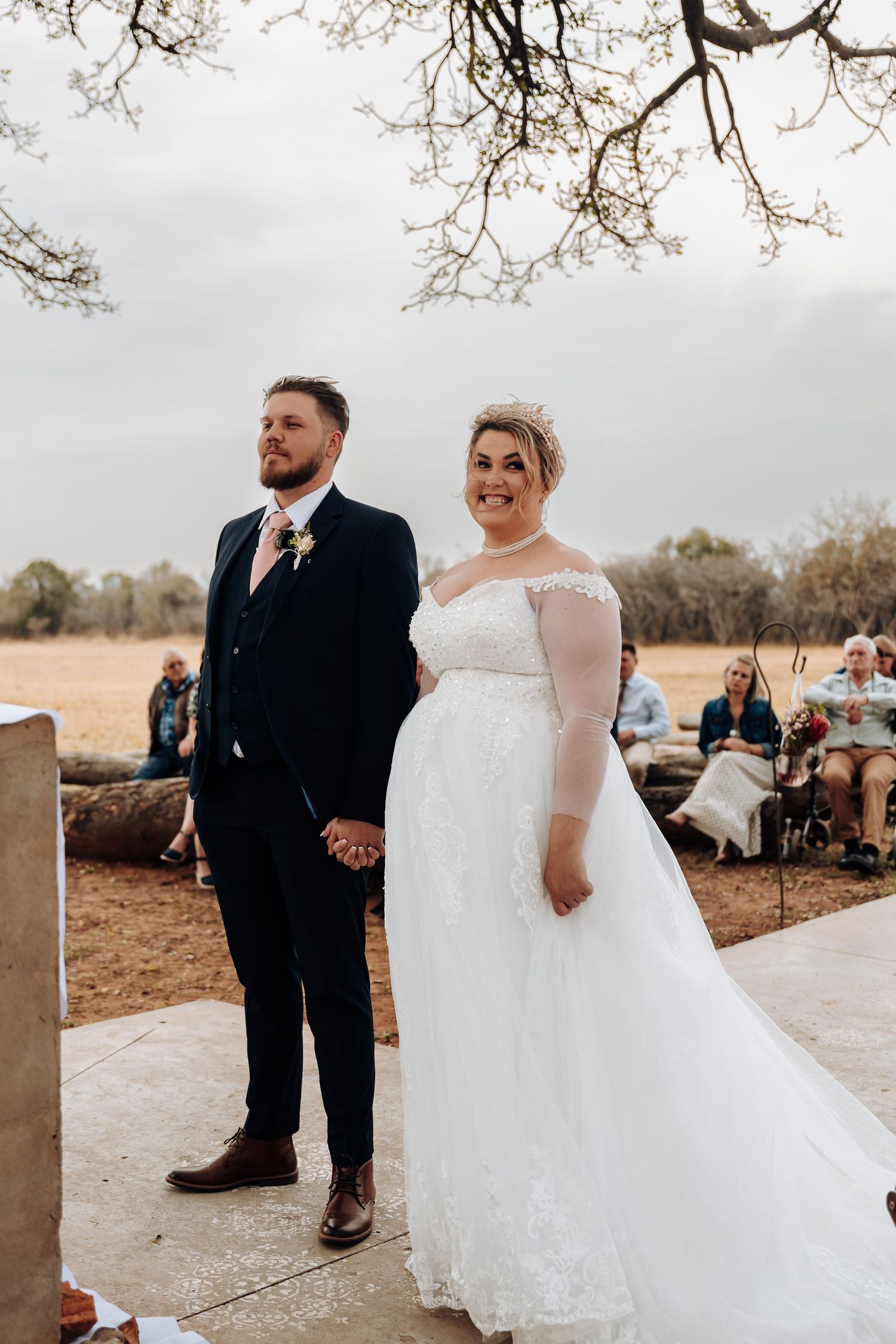 A couple shares tender moments during an outdoor wedding celebration in a rustic country setting.
