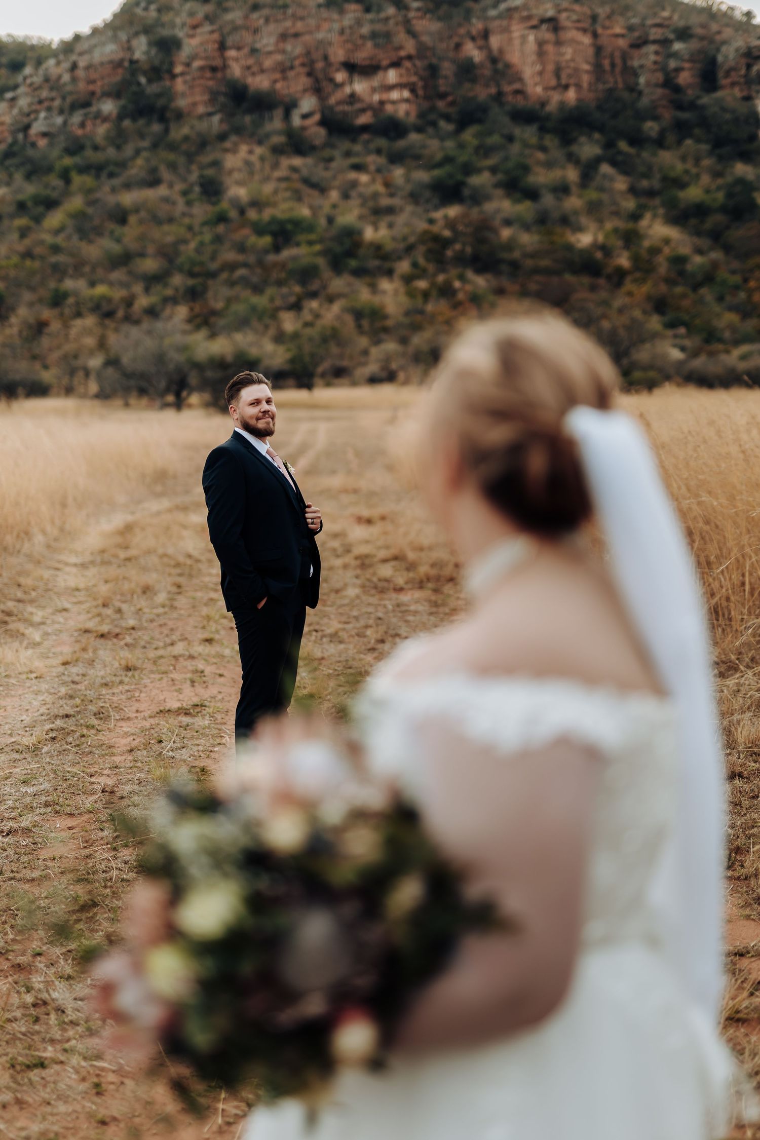 Romantic first look moment between newlyweds in a rustic desert landscape with red rock cliffs in background.