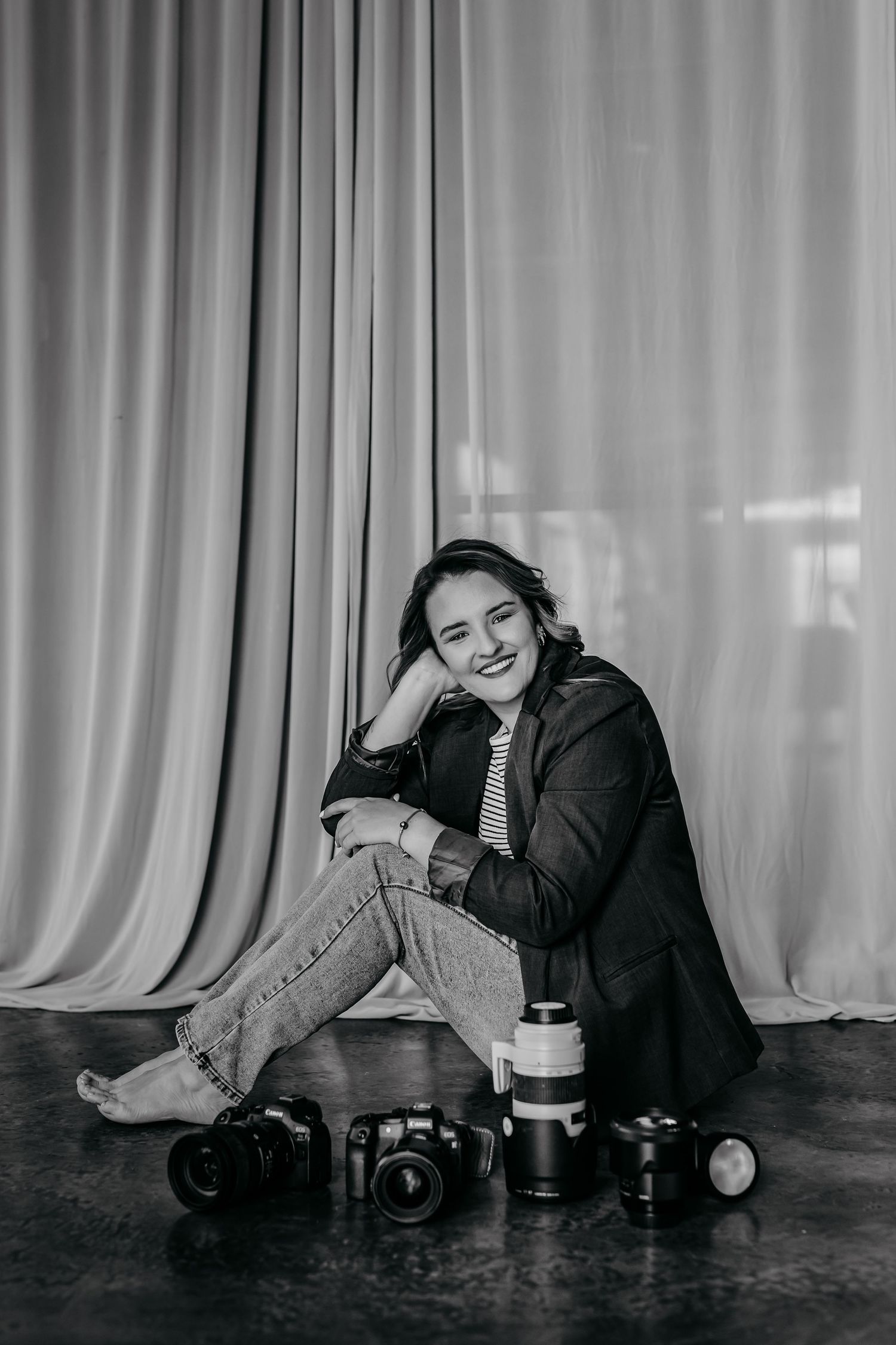 A black and white photo series showing a person reclining on the floor next to camera equipment and lenses.