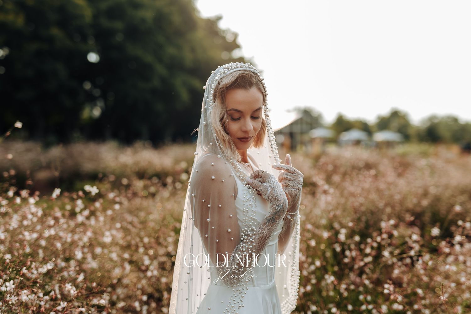 Ethereal bridal portrait in a field of white wildflowers at golden hour.