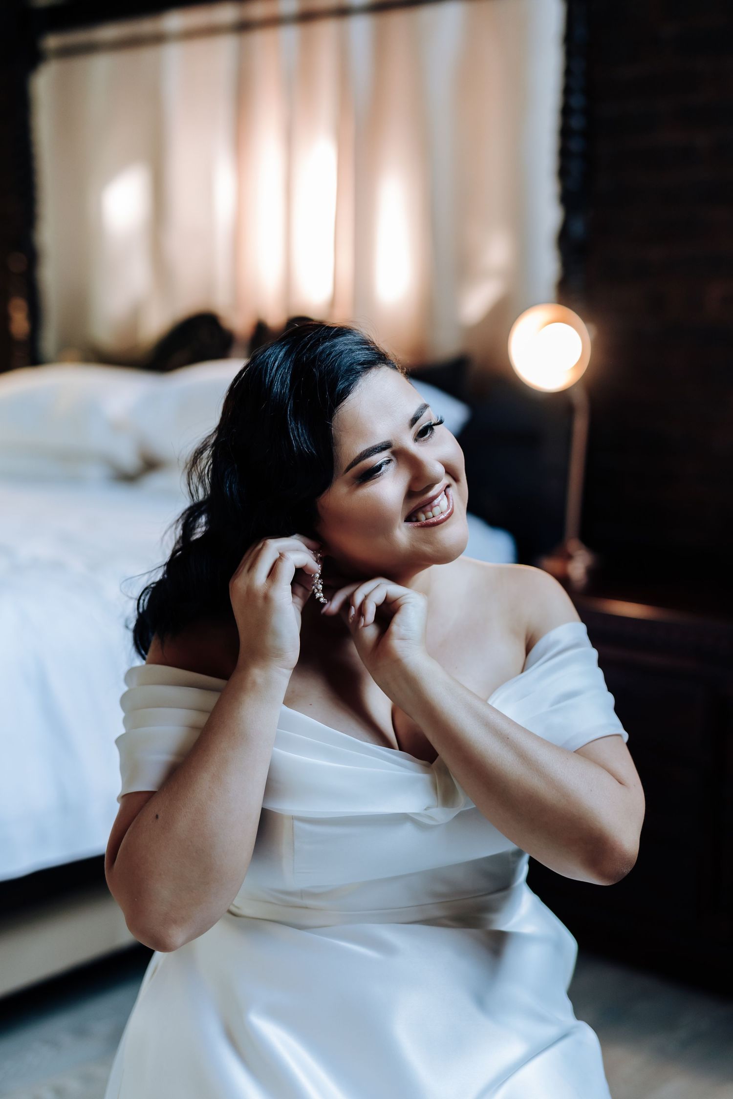 Person in white dress poses expressively during indoor photo session.