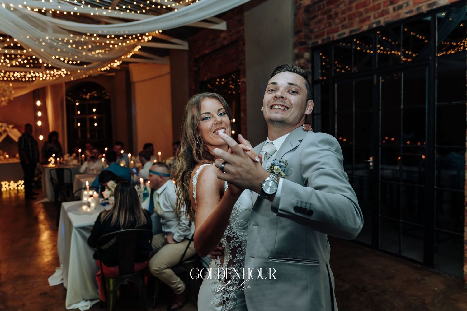 Couples dancing under twinkling lights at an elegant indoor wedding reception.