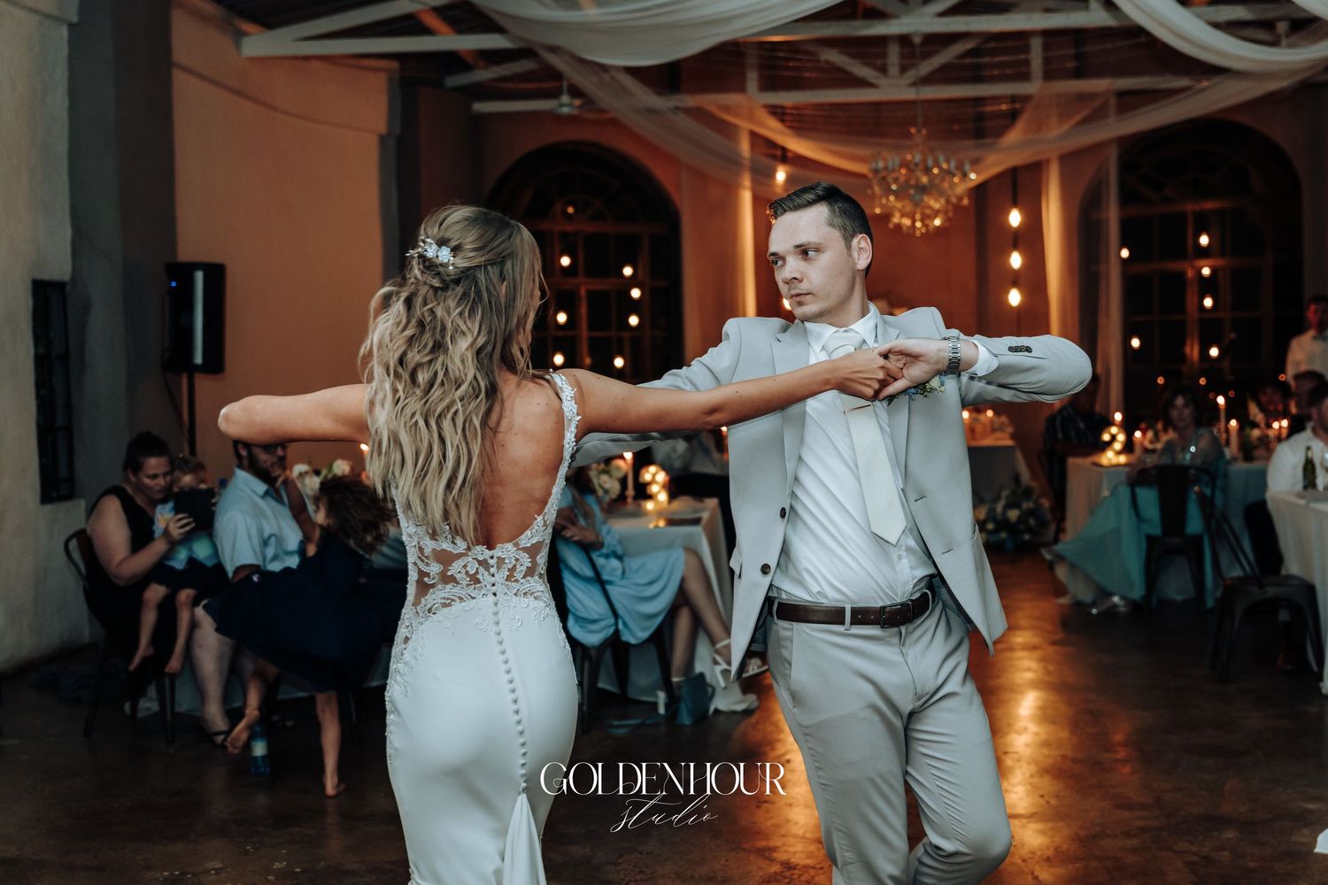 Couple dancing at their wedding reception in an elegantly lit venue.