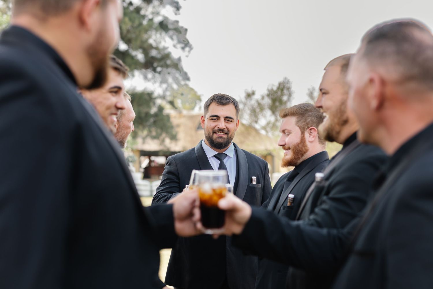 Wedding guests raise glasses in a celebratory toast during an outdoor reception gathering.