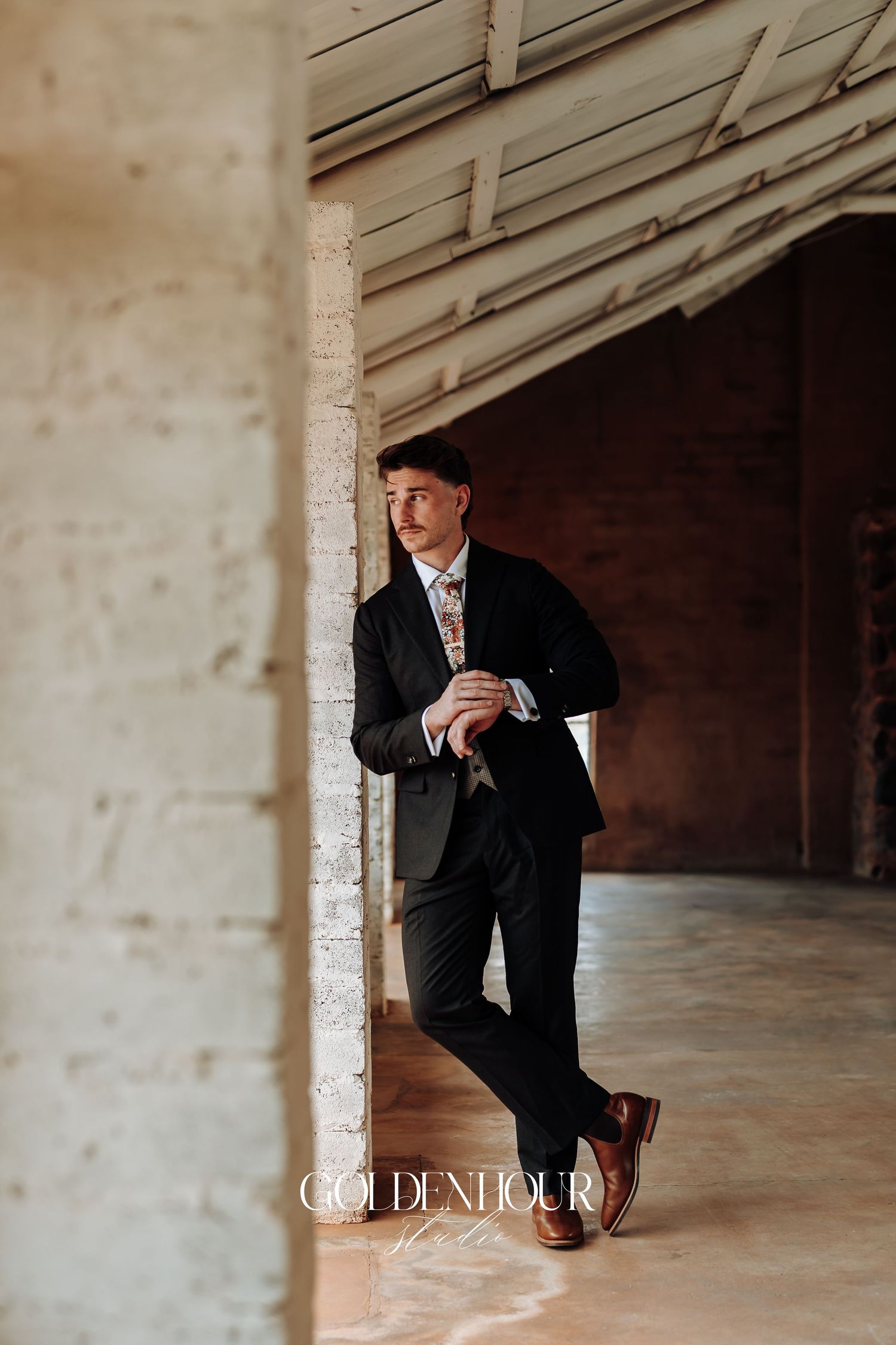 Artistic black and white portrait showing a suited figure in a minimalist architectural space.