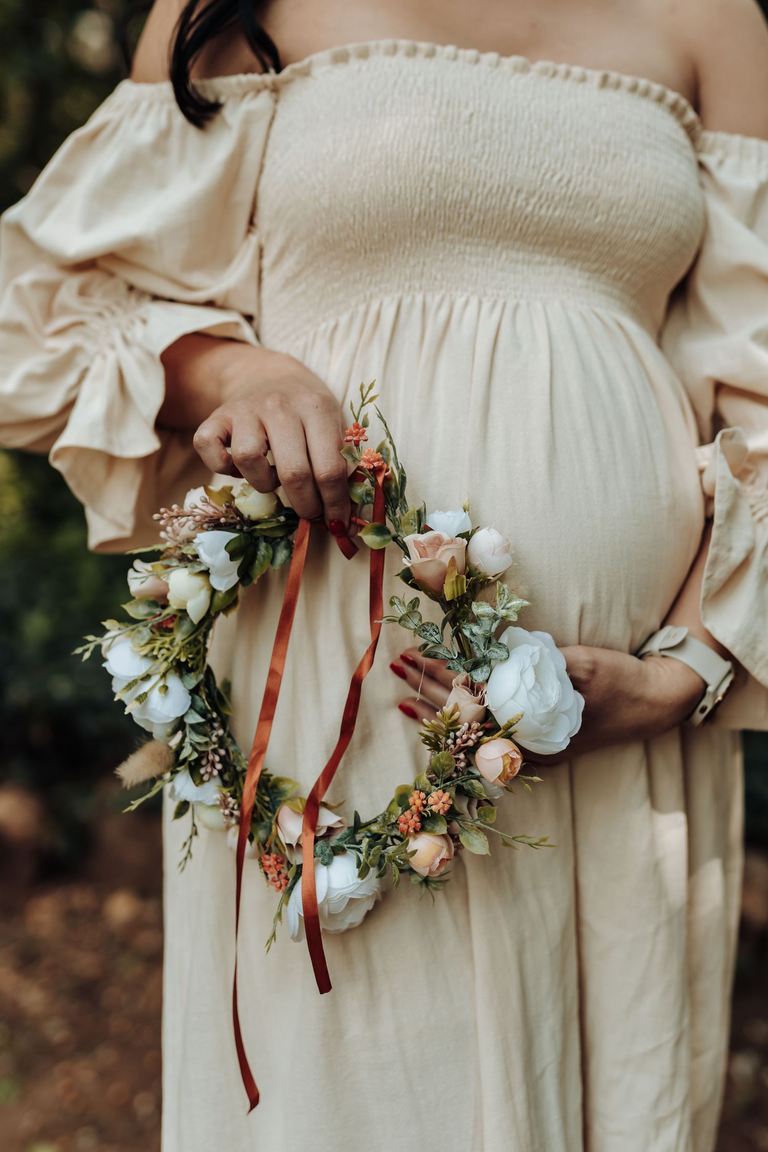 Close-up views of delicate floral corsages with white roses and greenery tied with brown velvet ribbons on a cream dress.