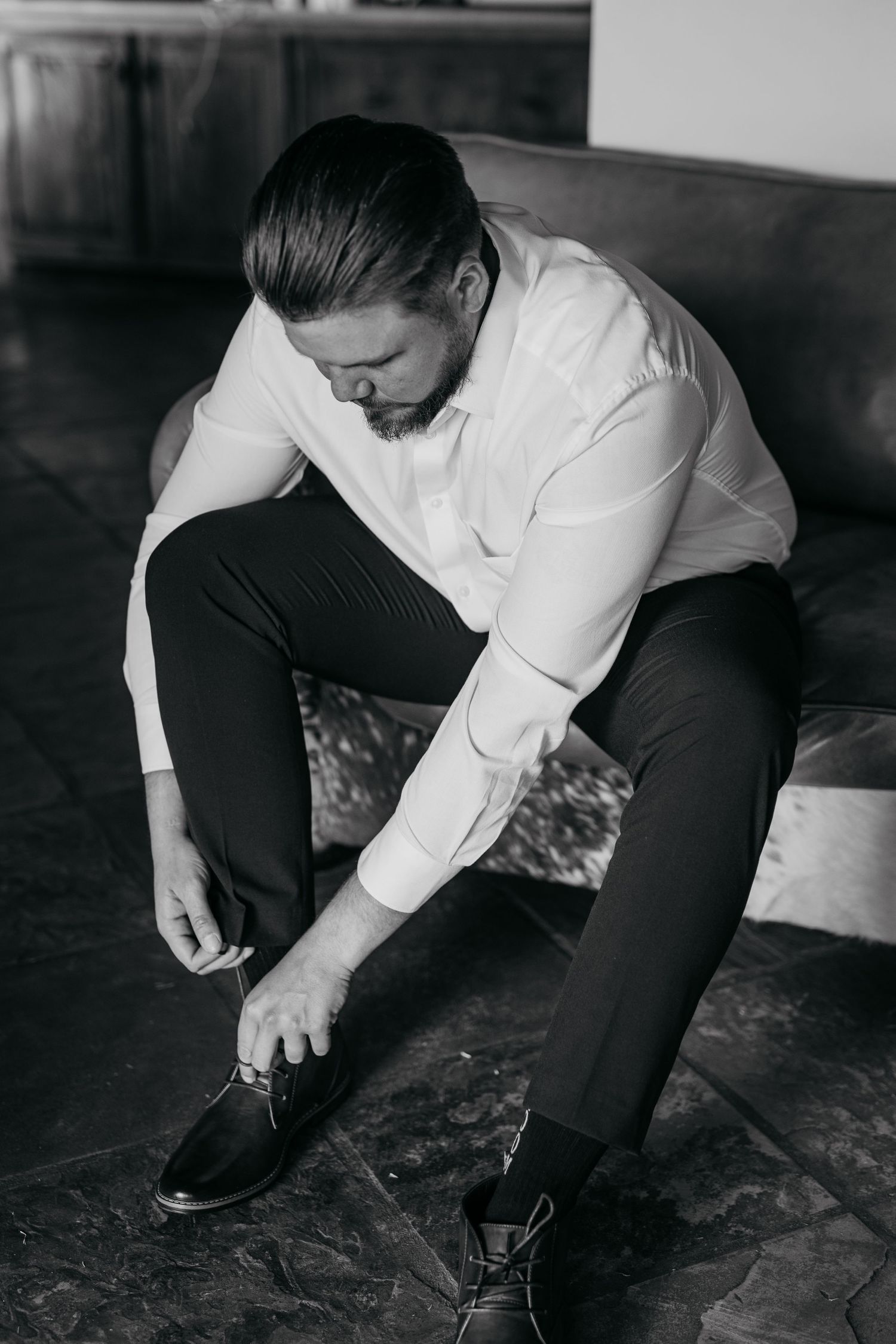 Black and white photo series showing someone tying their shoelaces while sitting down on a floor.