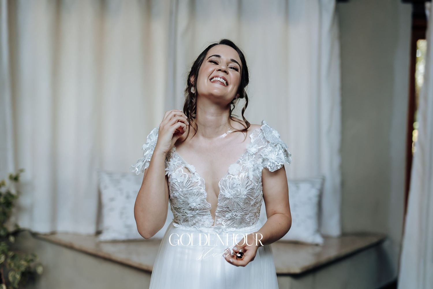 Radiant bride in a lace bodice wedding gown laughing joyfully while getting ready for her wedding day.