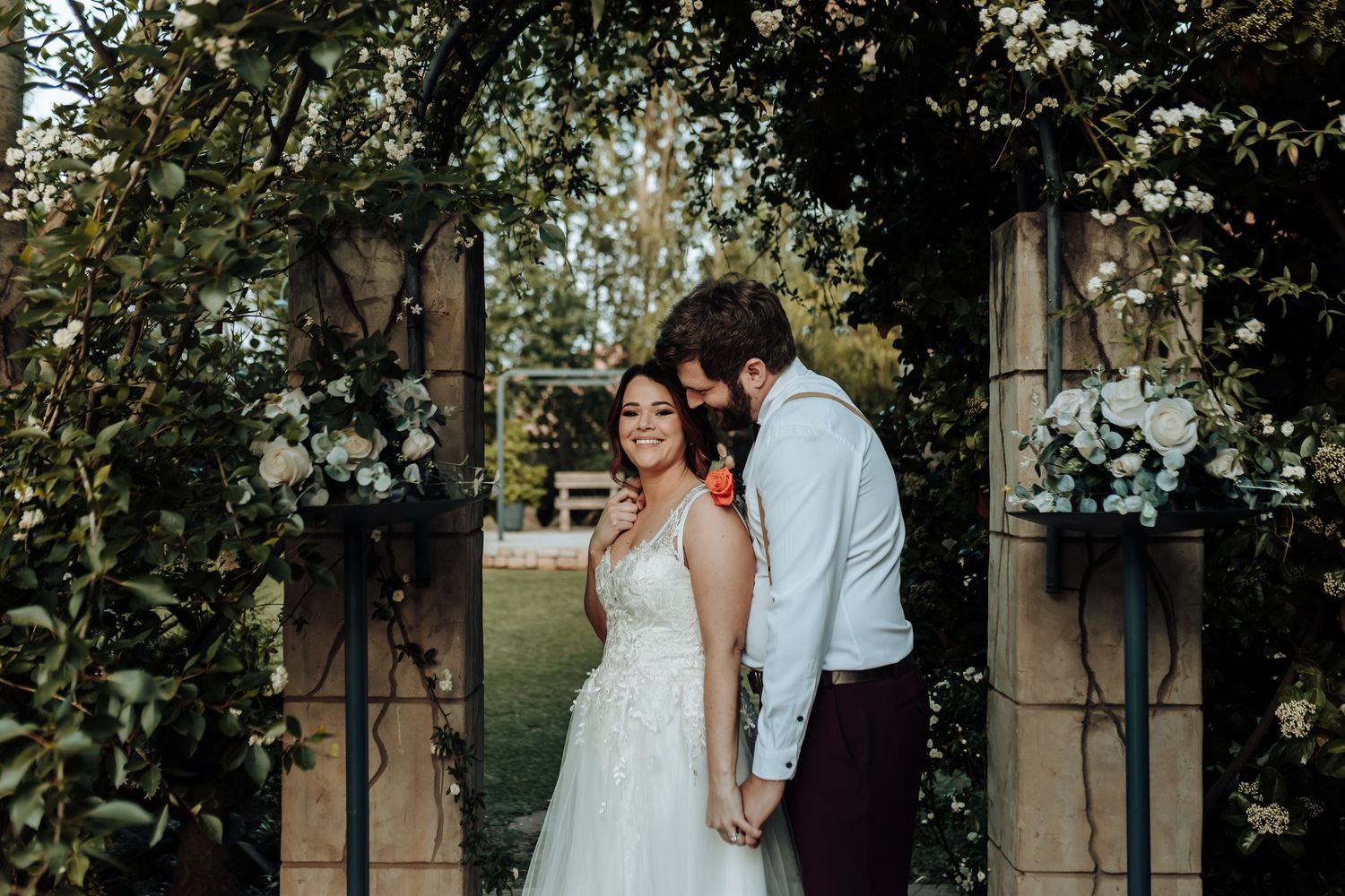 Romantic wedding portrait against rustic wooden doors with greenery.