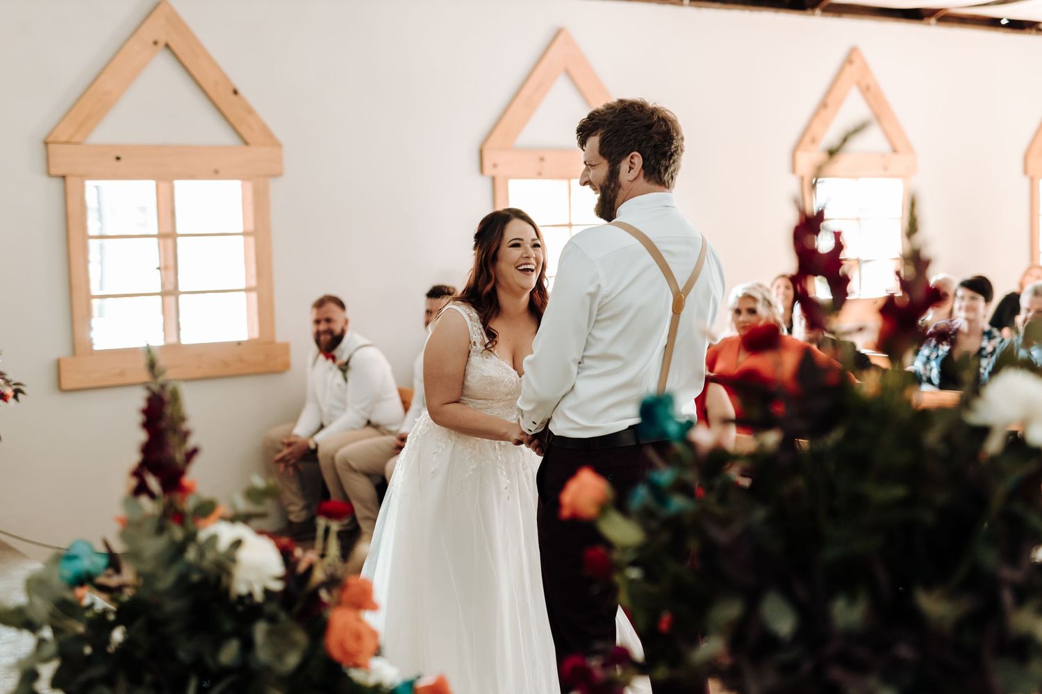 Wedding couple shares romantic moment in rustic venue decorated with wooden window frames.