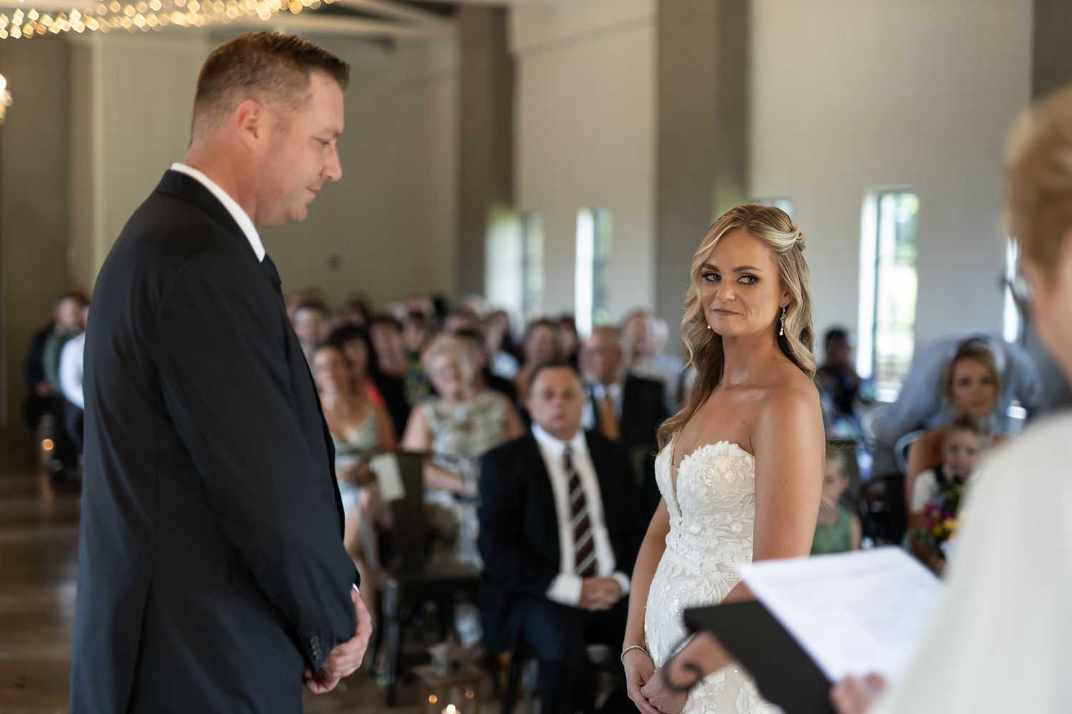 A couple exchanges vows during their wedding ceremony in a bright indoor venue.