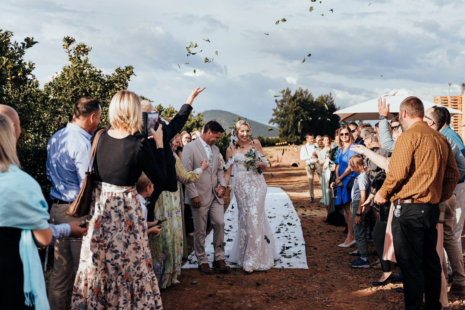 Wedding guests throw confetti as newlyweds walk through a celebratory exit pathway.