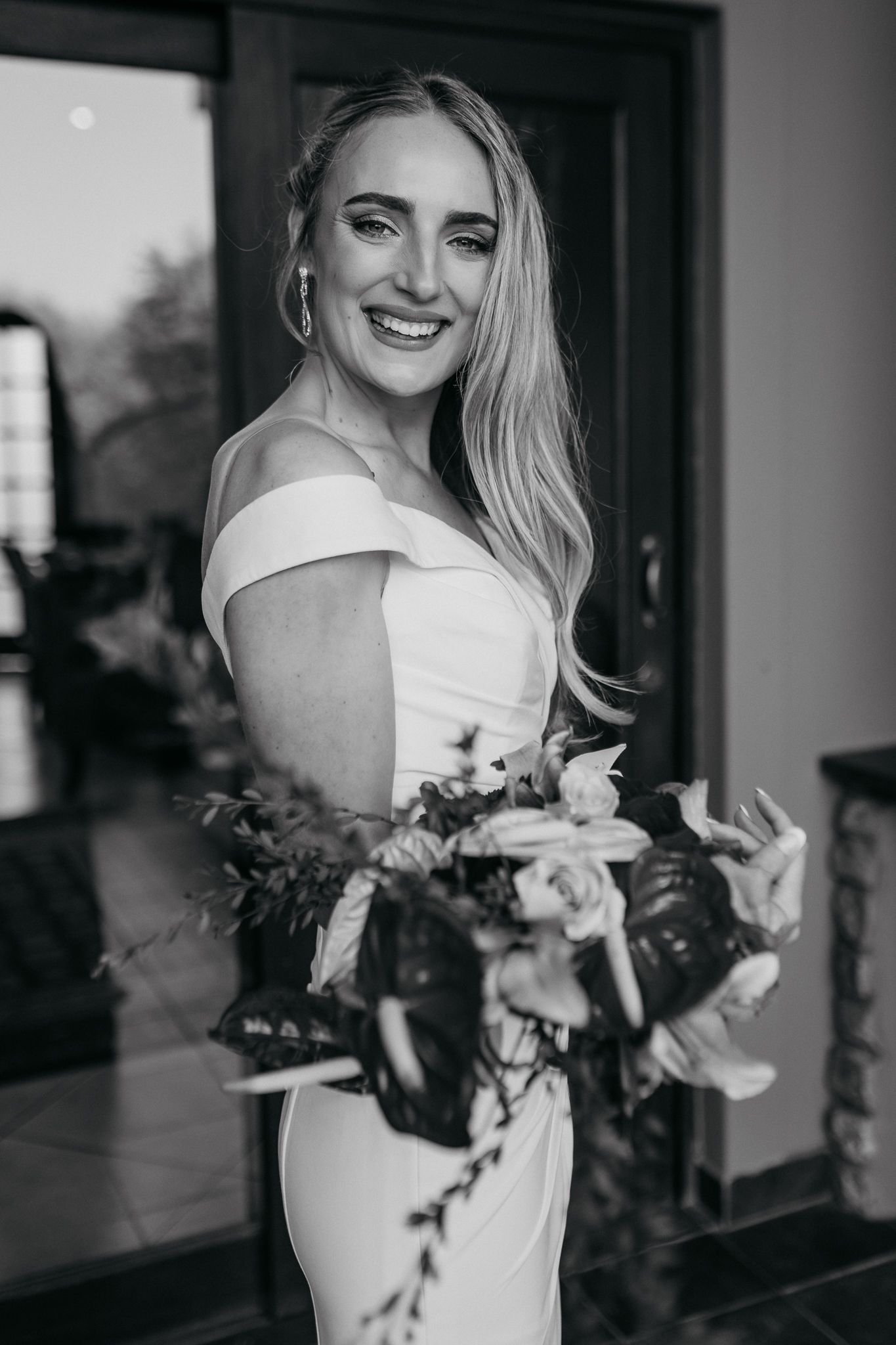 Black and white bridal portrait with natural bouquet and off-shoulder gown.