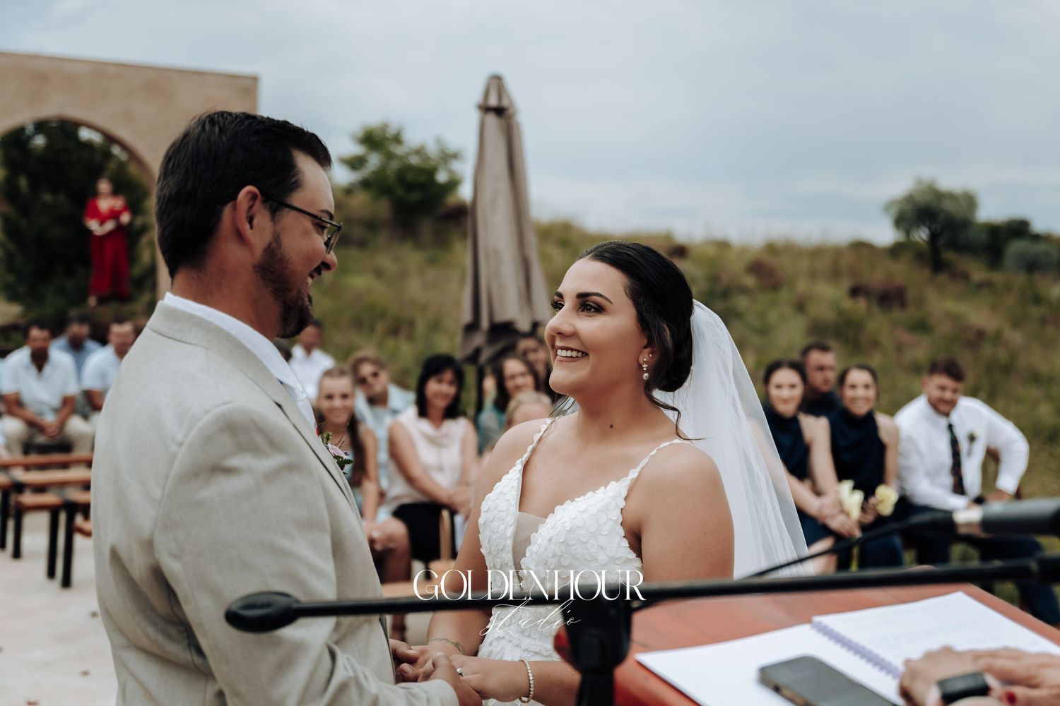 Outdoor wedding ceremony with guests gathered under cloudy skies.