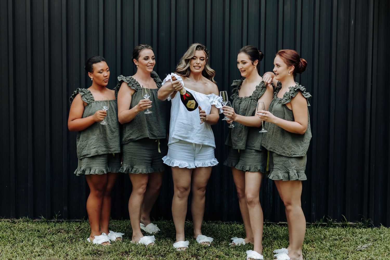 Group wearing matching olive green outfits laughing together outdoors.