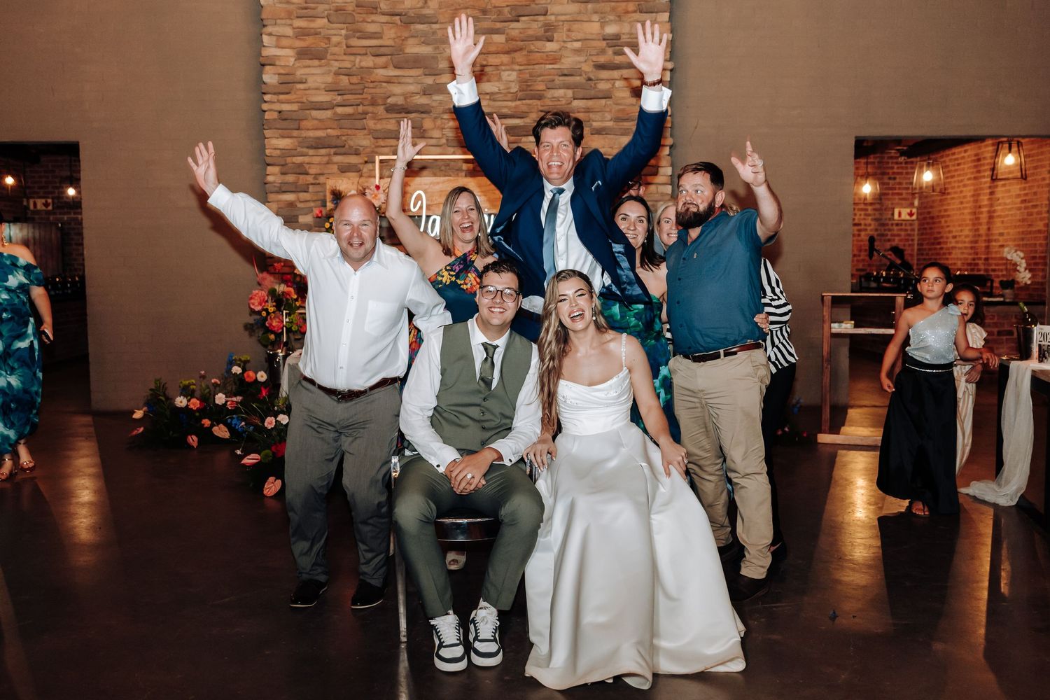 Wedding guests pose enthusiastically for a fun group photo at the reception.