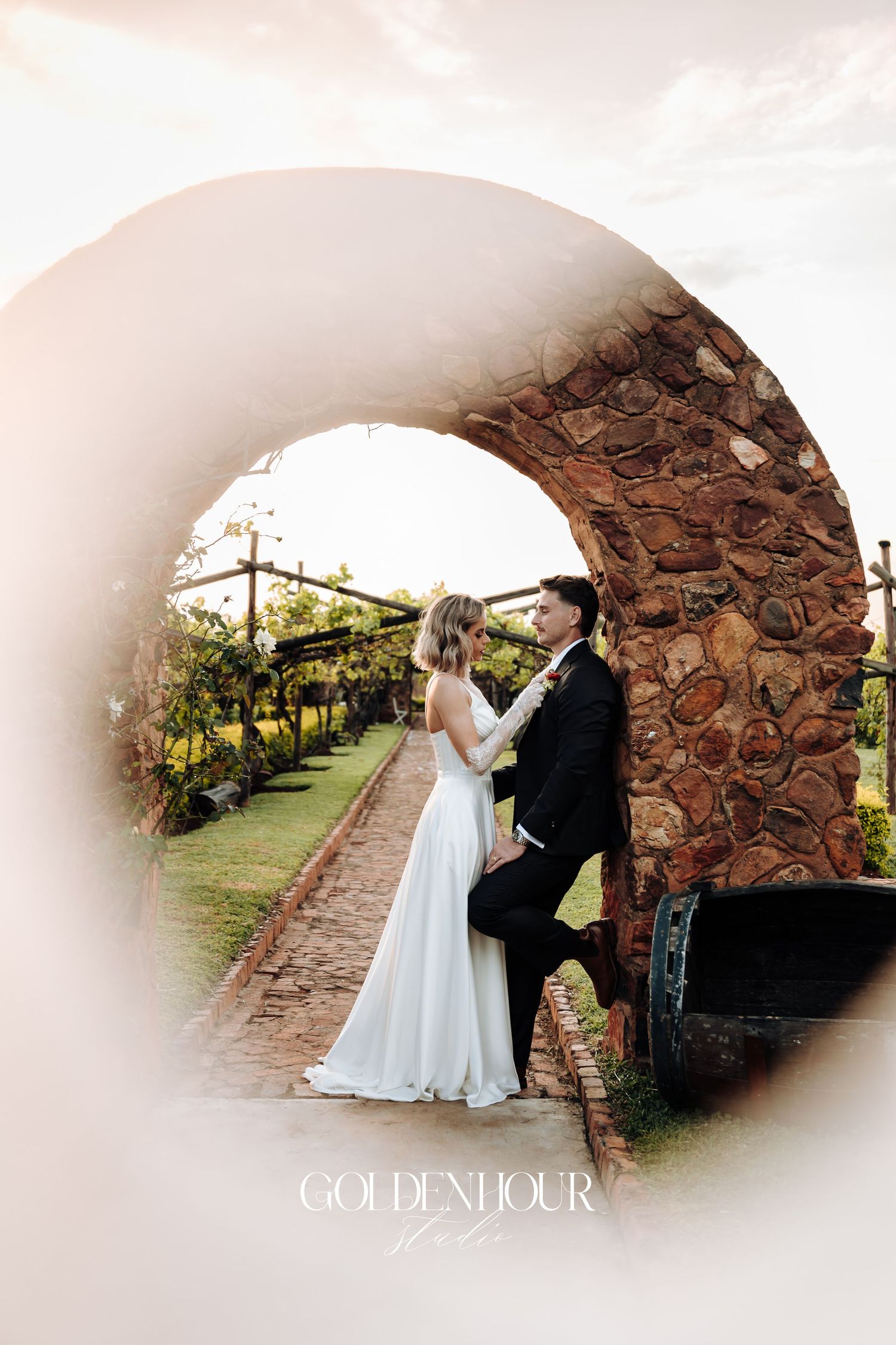 Wedding couple sharing an intimate moment under a stone archway.