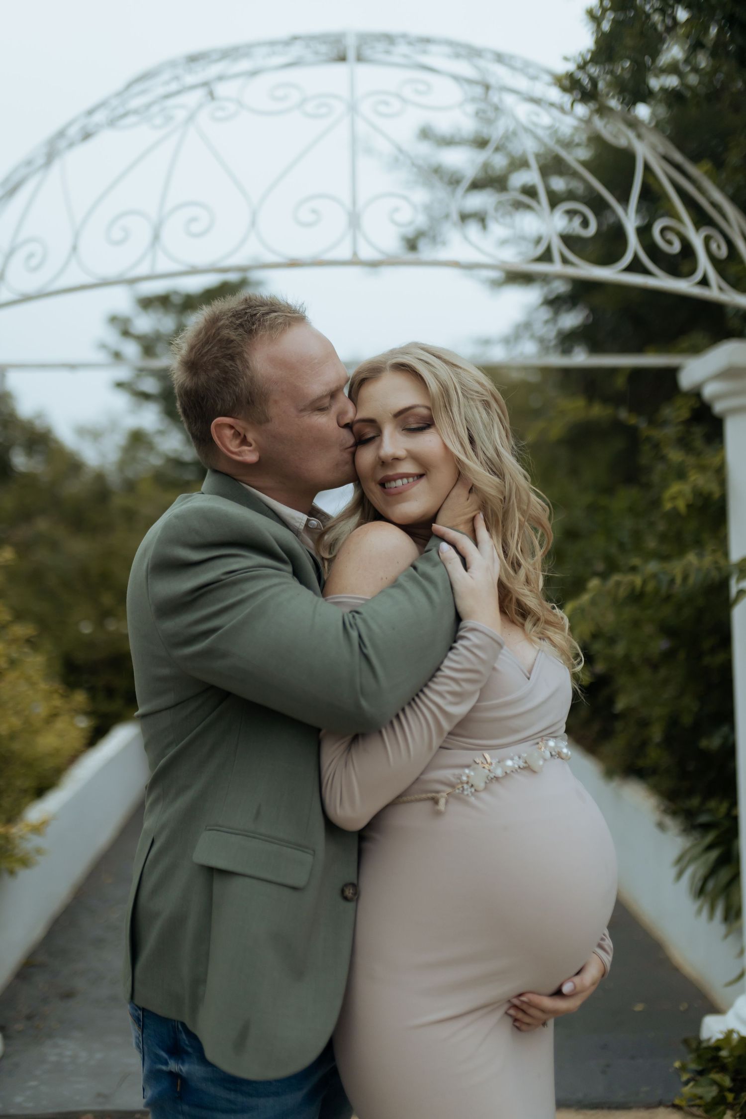 A romantic maternity photoshoot capturing tender moments in a garden setting.