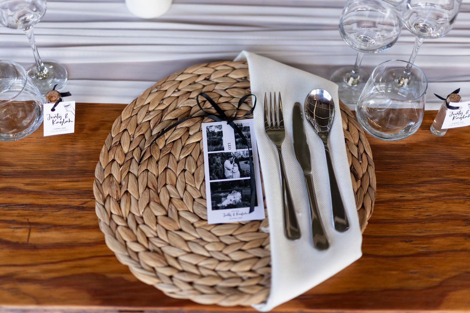 Overhead view of a table setting with woven placemat, photo strip, and elegant silverware.