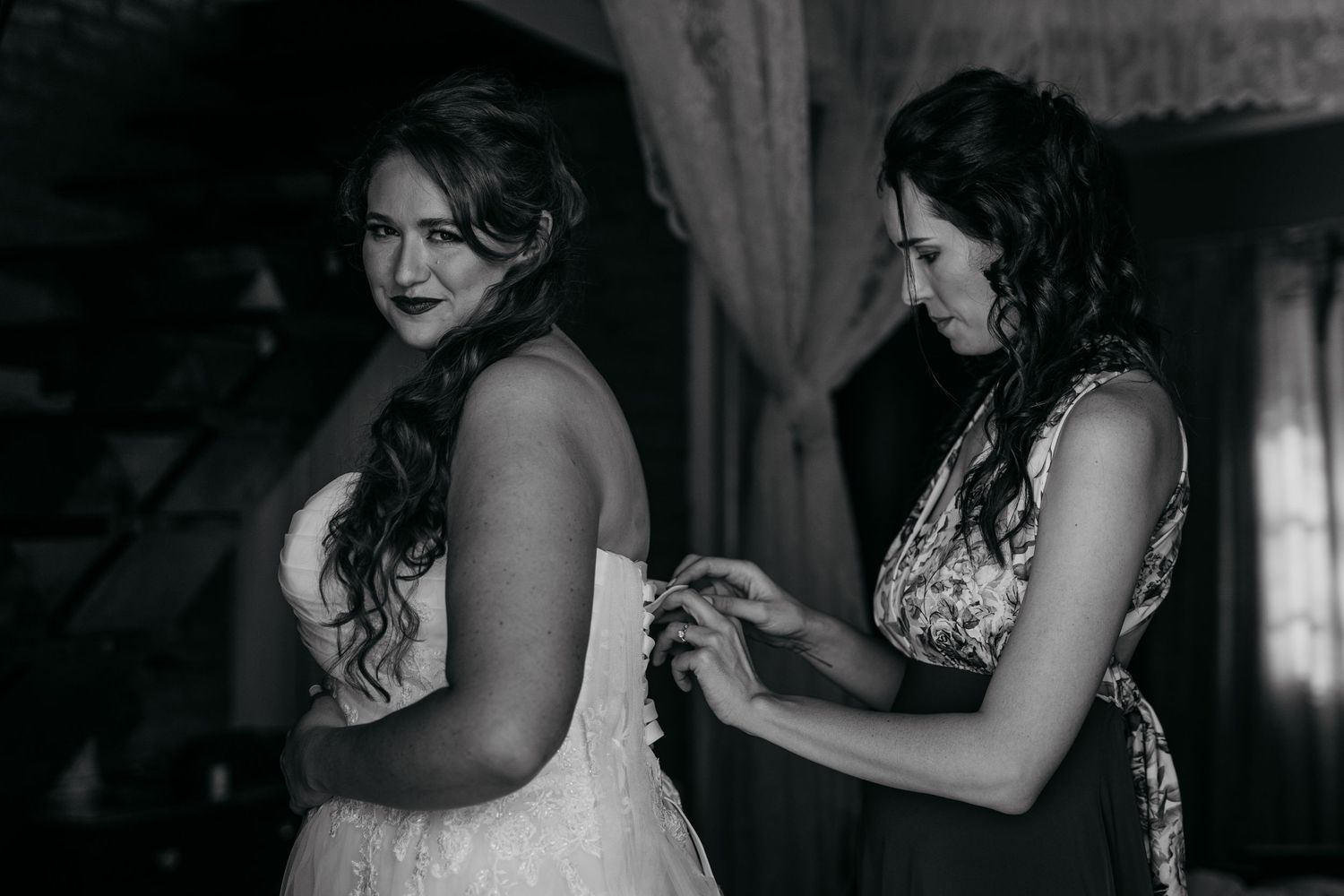 Black and white image of a wedding dress being adjusted during preparation.