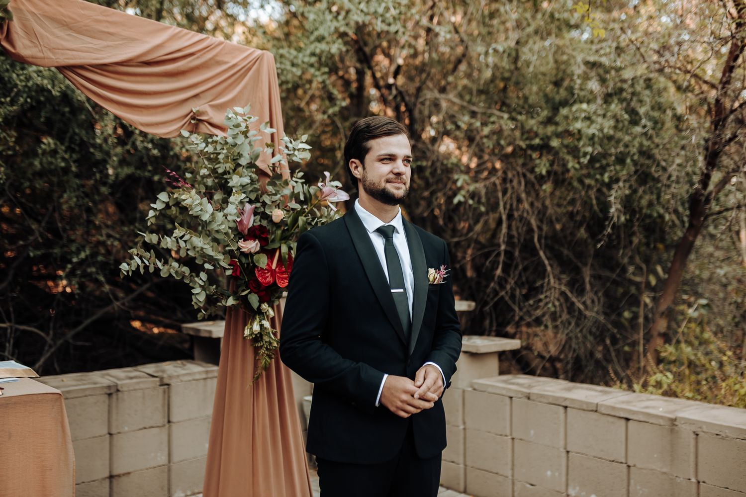 An outdoor wedding setup with draped fabric and floral arrangements against a natural backdrop.