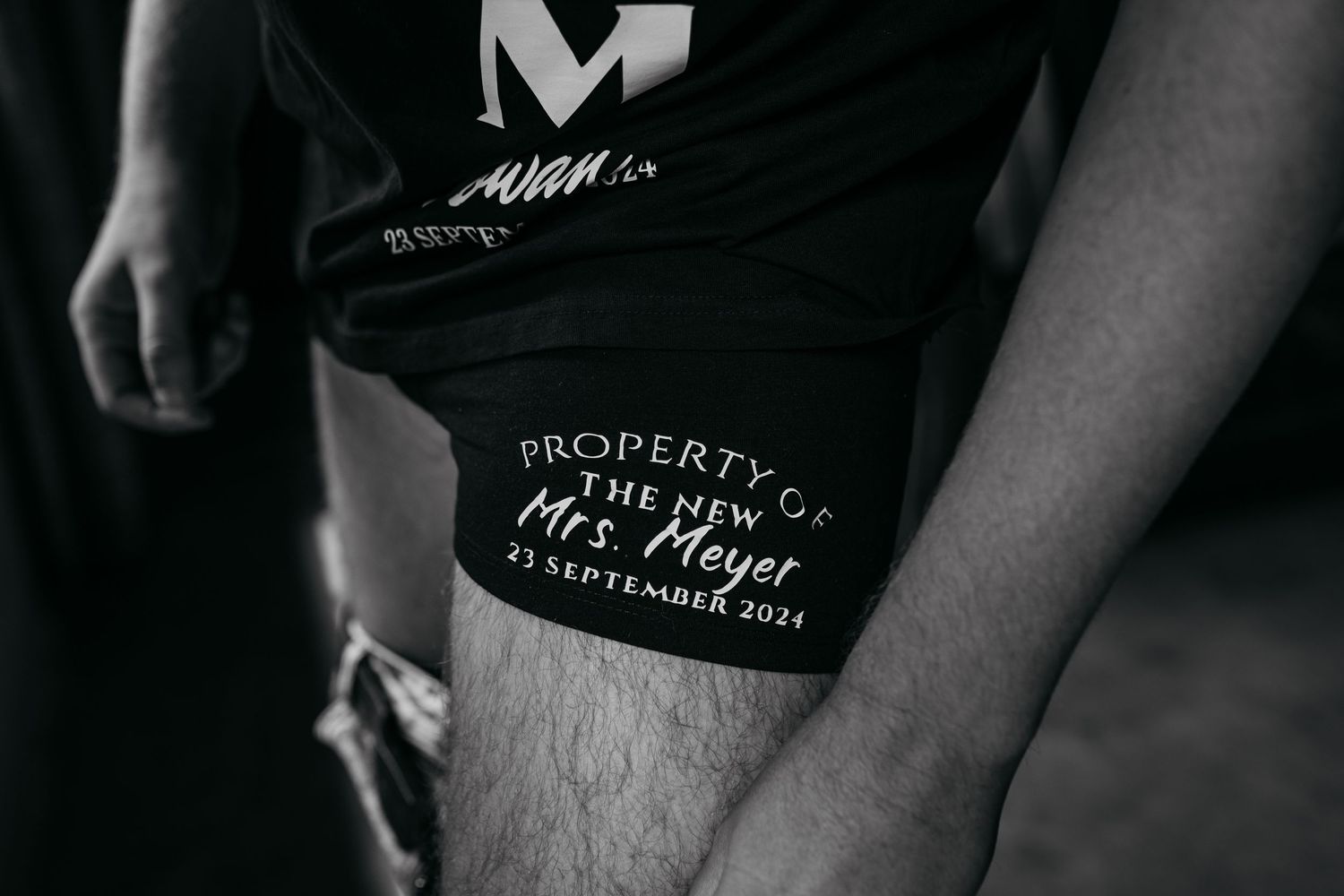 Close-up detail shot of black clothing with white text saying 'Property of'.