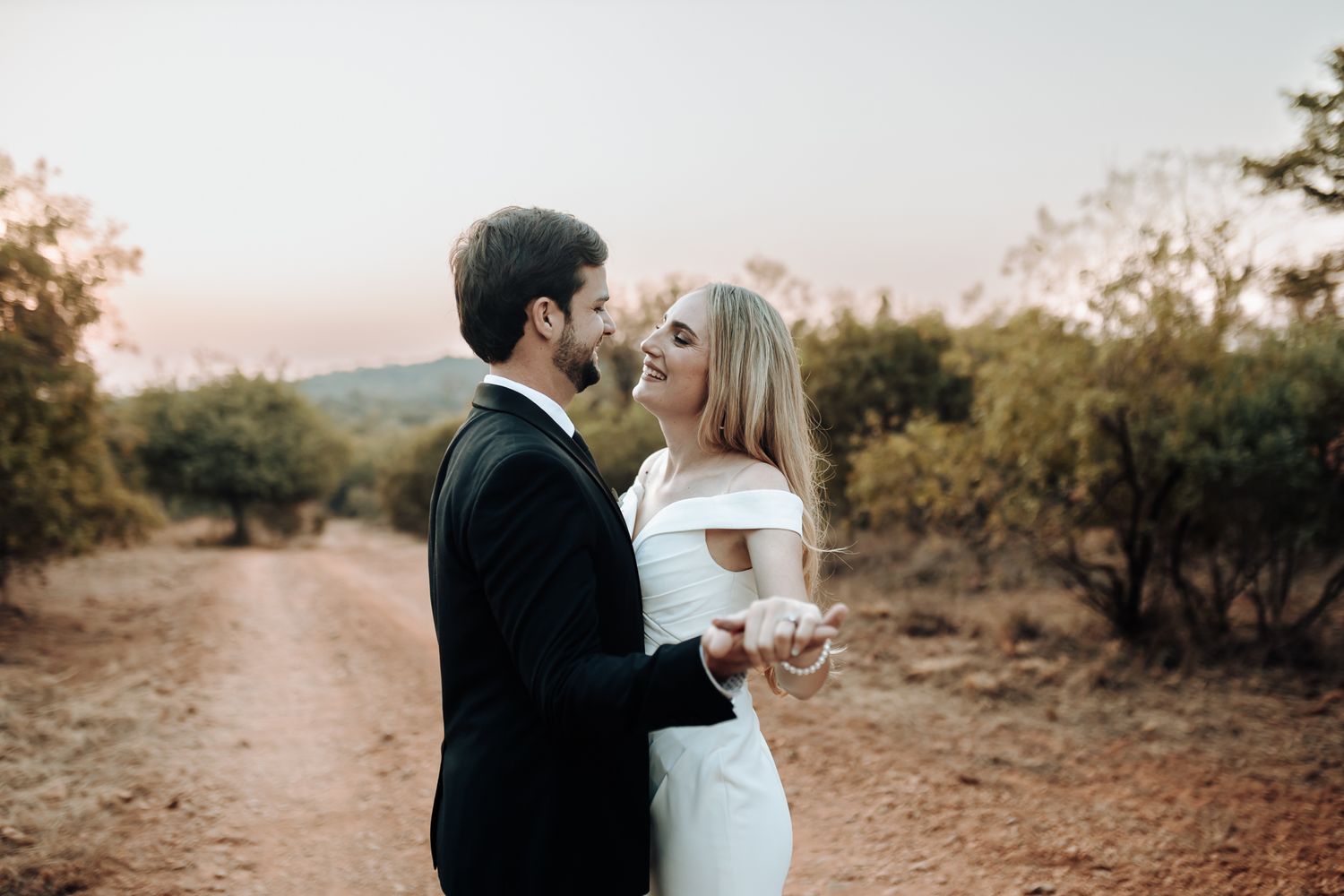 A romantic sunset portrait of a couple sharing an intimate moment on a countryside path.