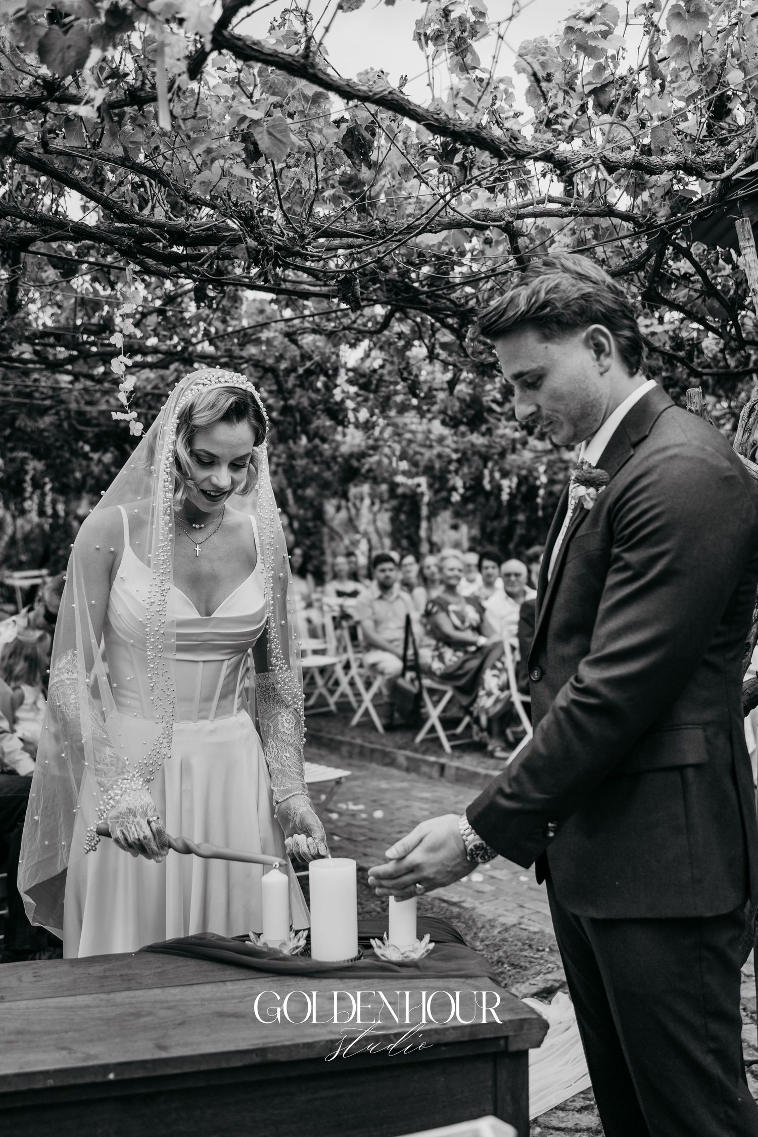 Black and white photo of couple performing unity ceremony outdoors.
