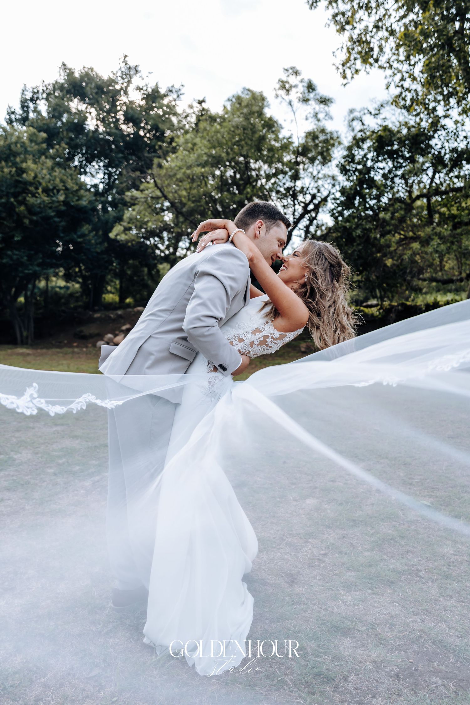 Dramatic outdoor wedding dip pose with flowing white dress against natural landscape.