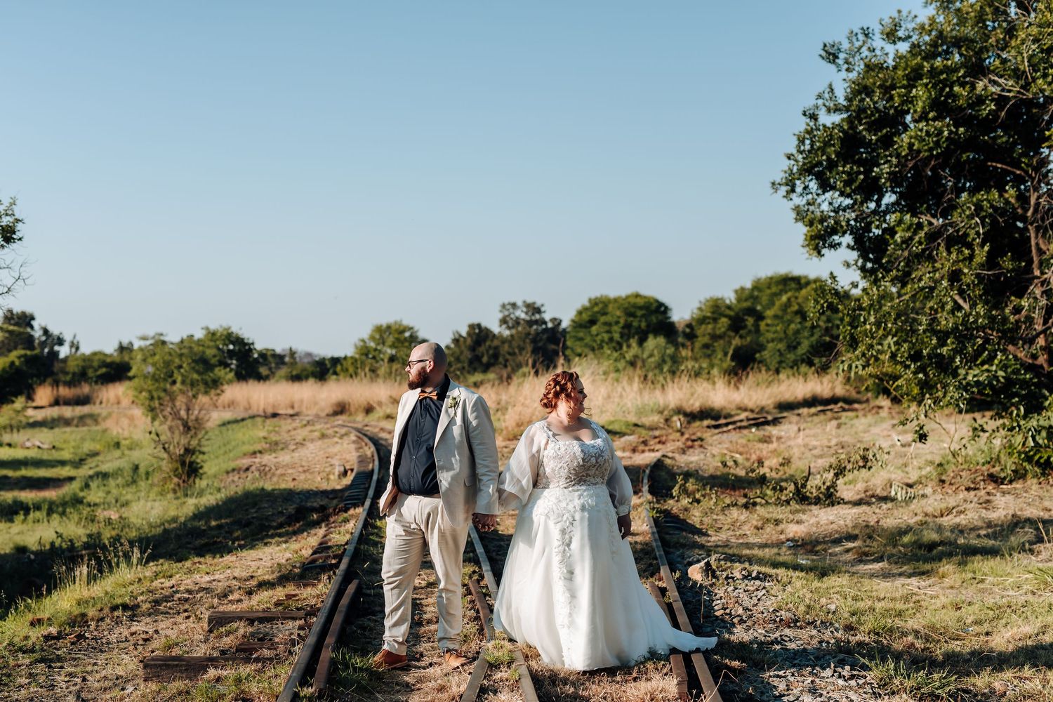 Newlywed couple walking through a scenic California vineyard during golden hour on their wedding day.