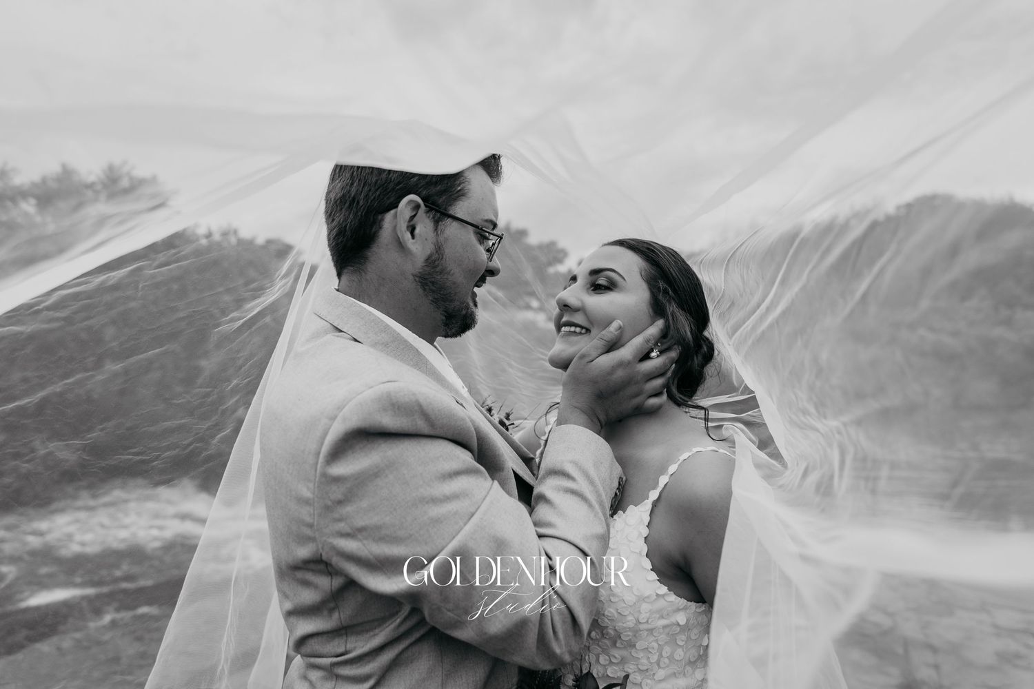 Intimate wedding portrait with flowing veil creating dramatic effect.