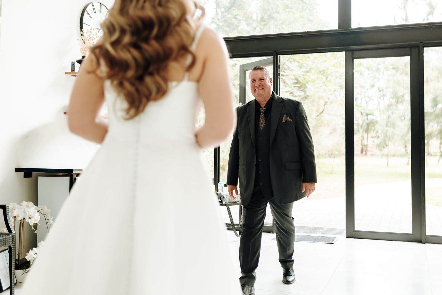 Elegant wedding couple shares intimate moments in a bright modern venue with large windows.