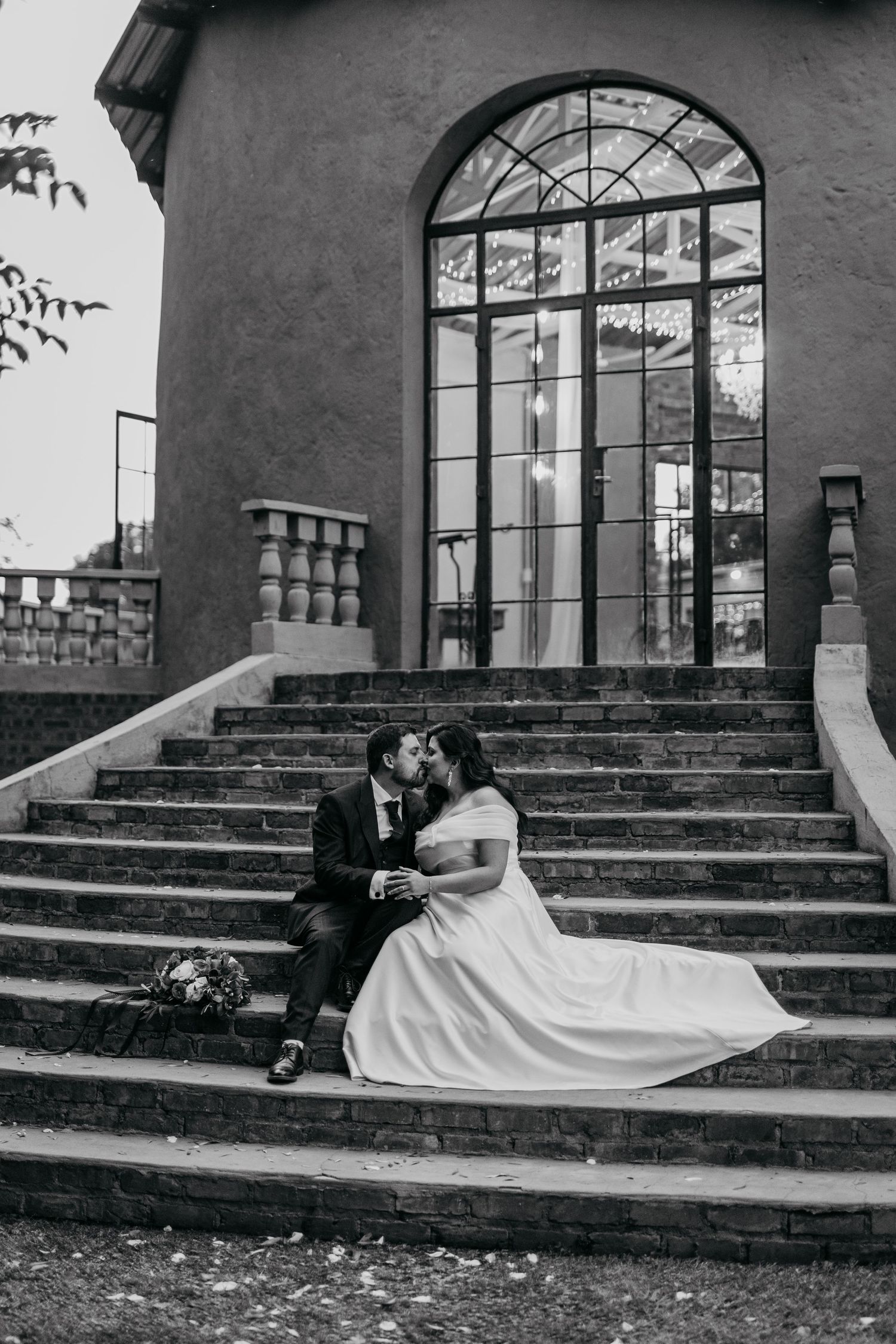 A series of black and white wedding photos showing a couple posing on stone steps with arched windows.