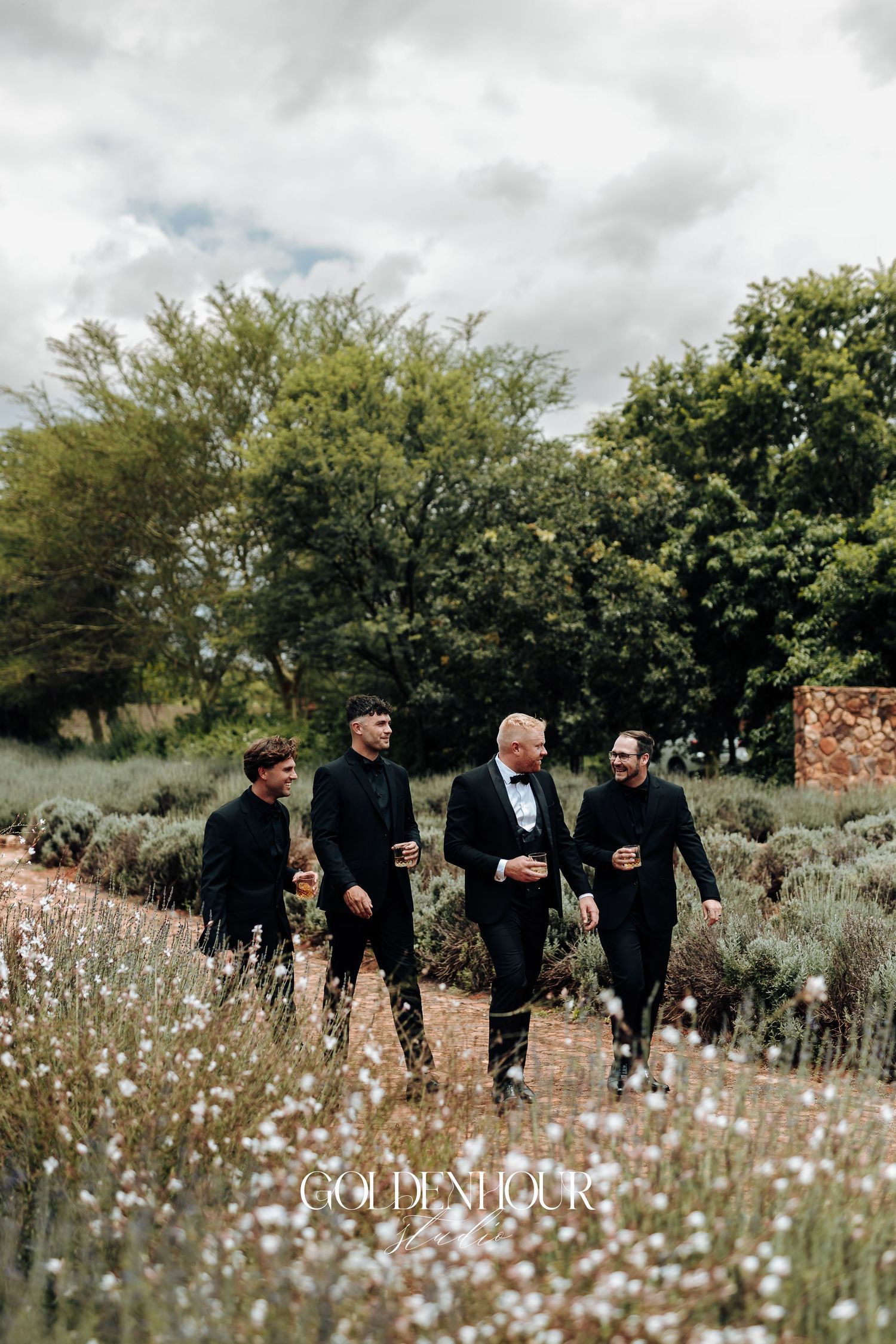A group walks together through a wildflower meadow on a cloudy day with trees in the background.