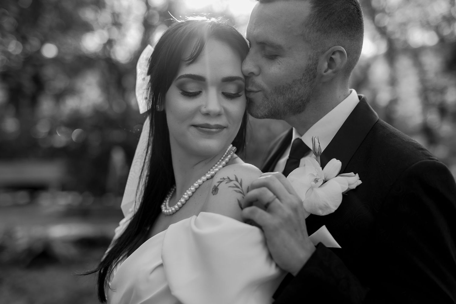 Black and white romantic wedding photo of a couple embracing while dancing outdoors.