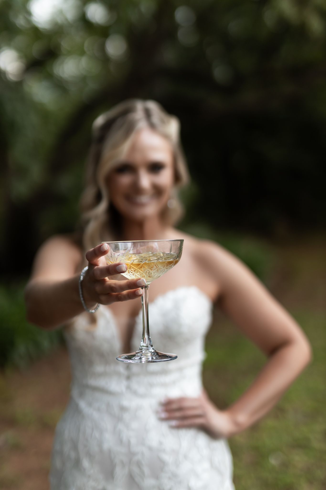 A celebratory moment captured as a bride raises a champagne coupe in the garden.