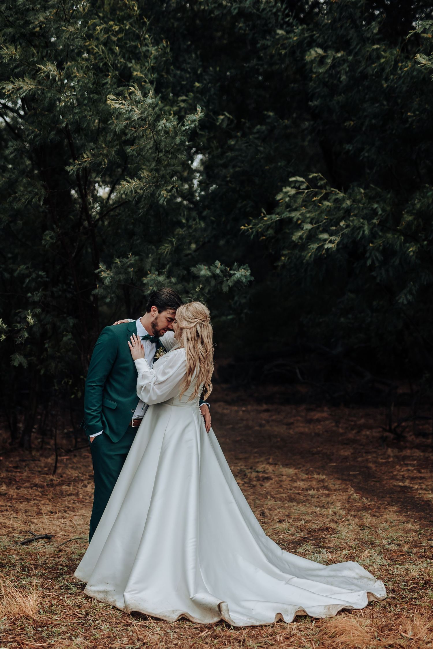 Wedding couple shares an intimate moment in a forest clearing.