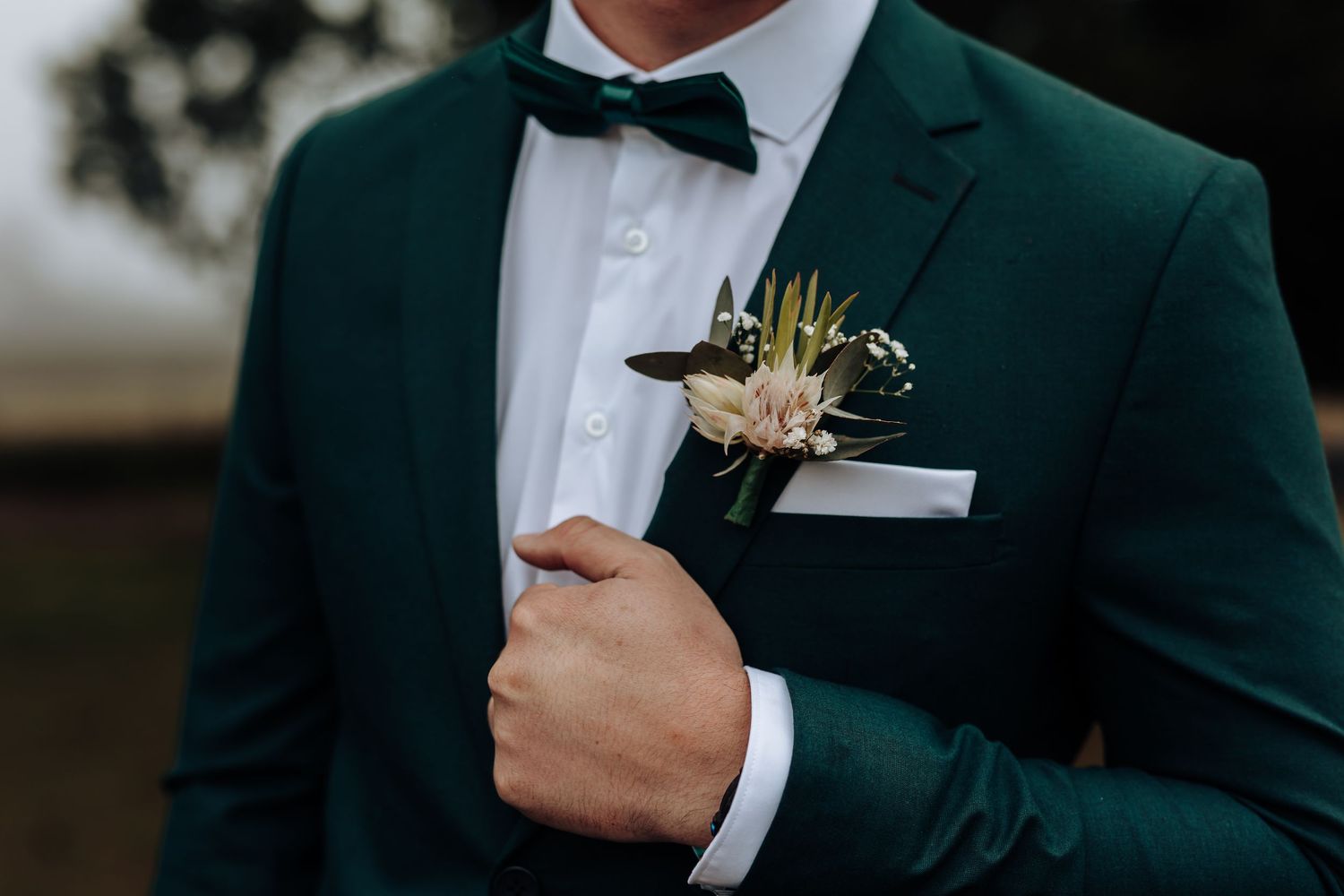 Close-up detail of emerald green tuxedo with boutonniere and black bow tie.
