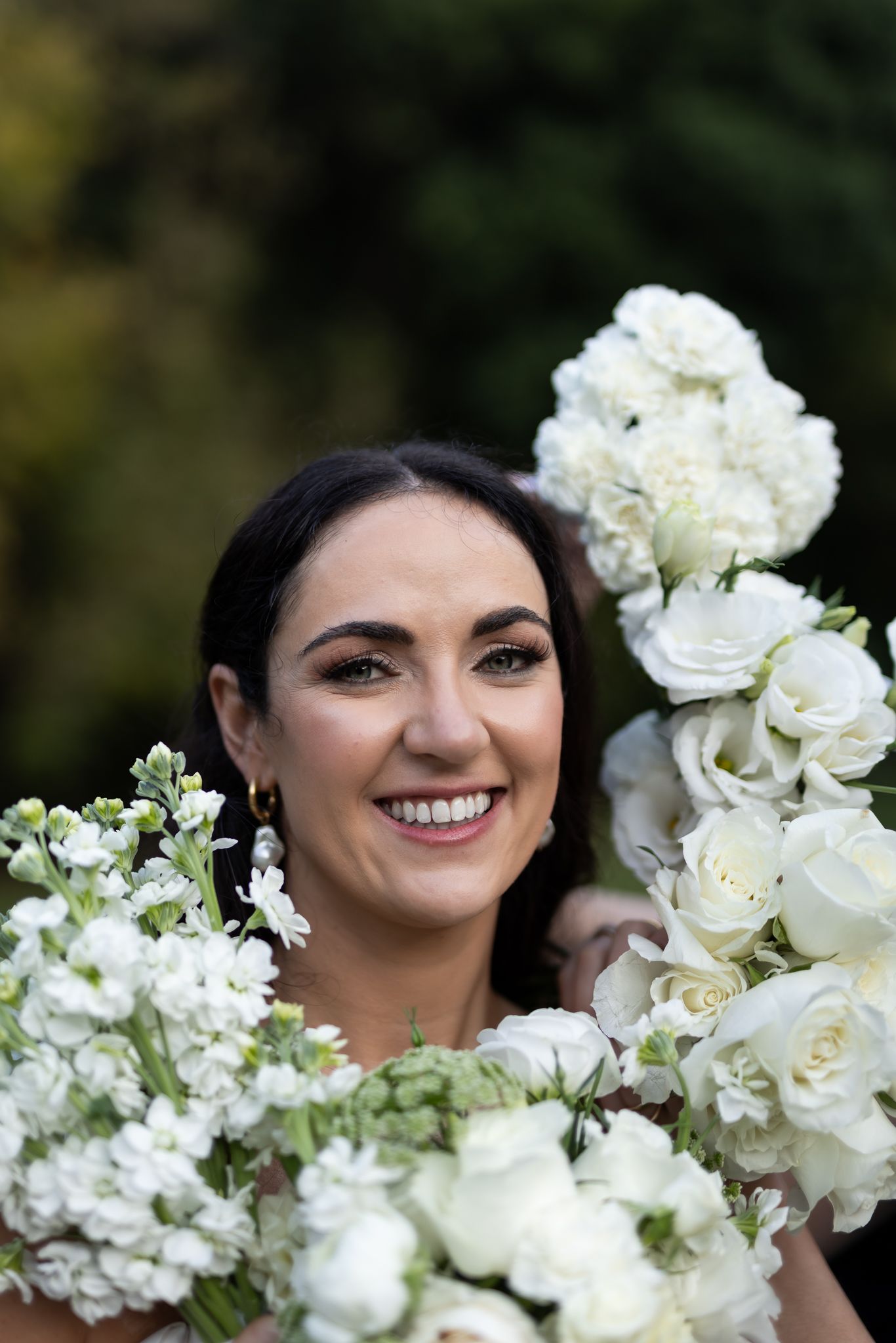 Beautiful bouquet of white roses frames close-up shot against natural outdoor background.