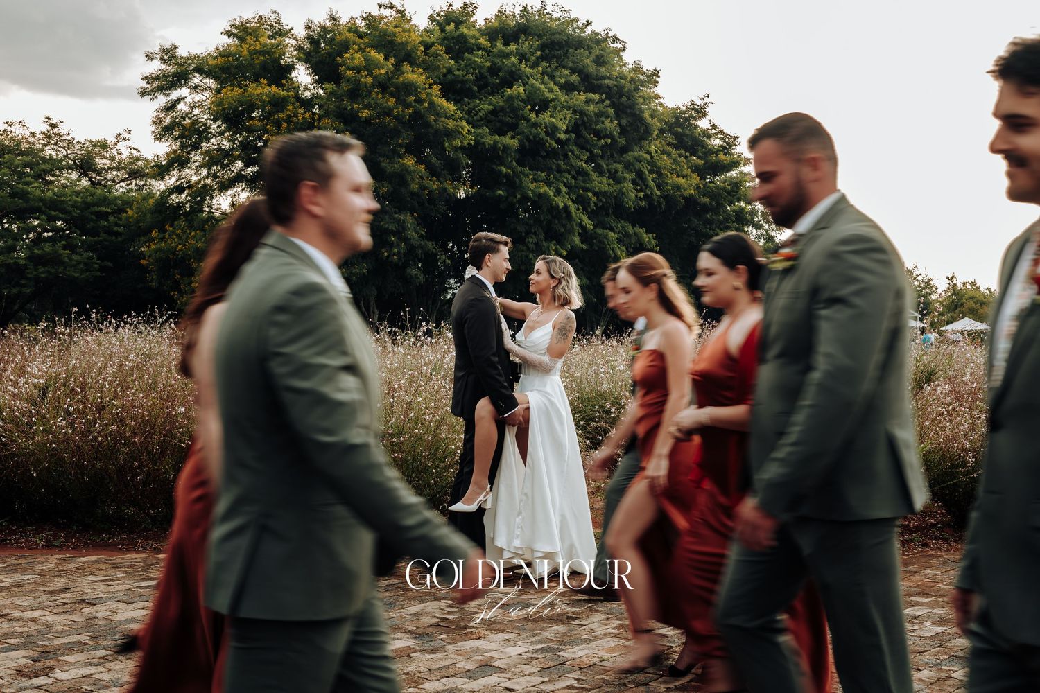 Wedding party members walking and celebrating together outdoors during golden hour.