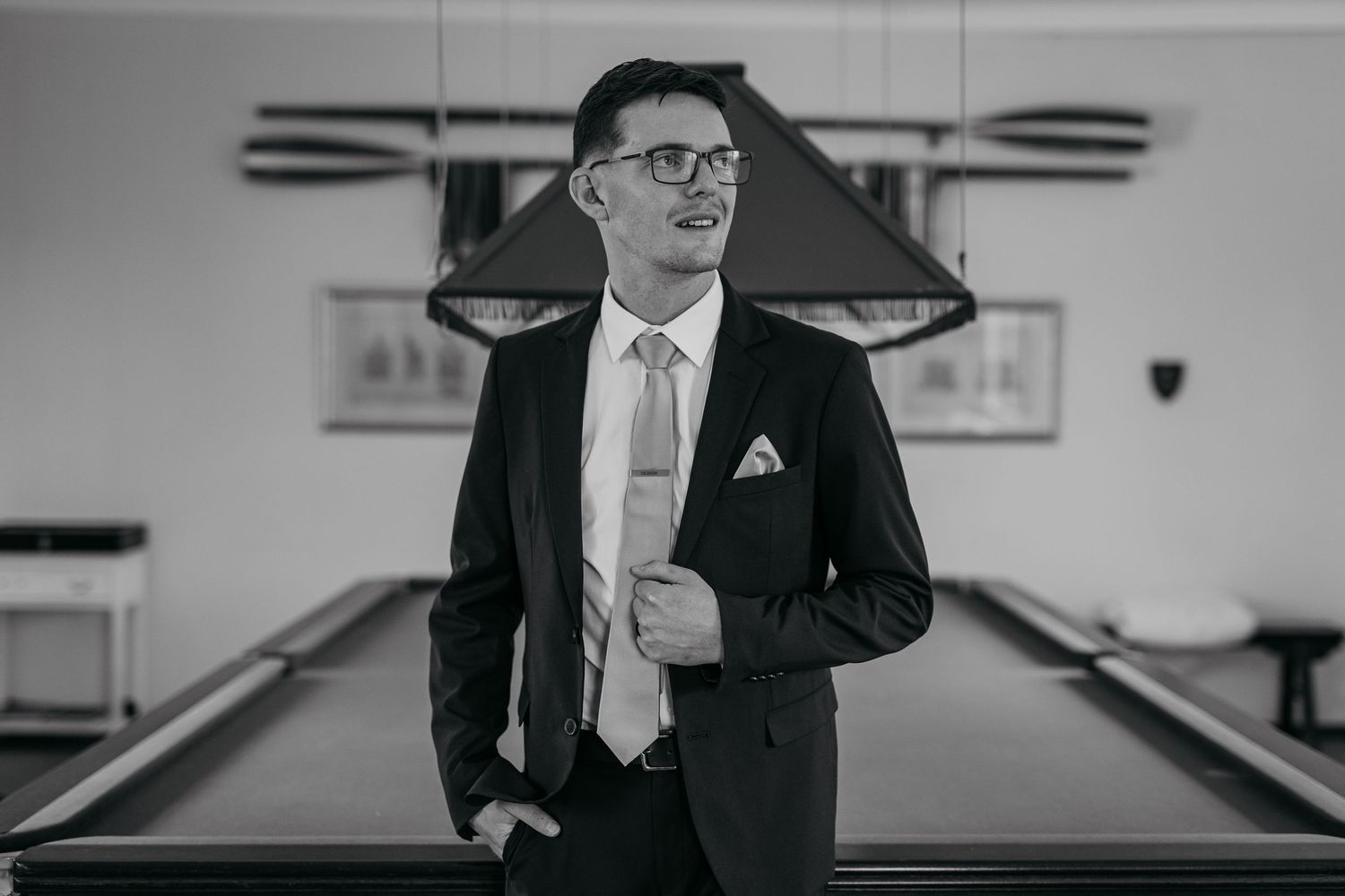 Black and white photograph shows a person in a suit and glasses standing in a bowling alley.