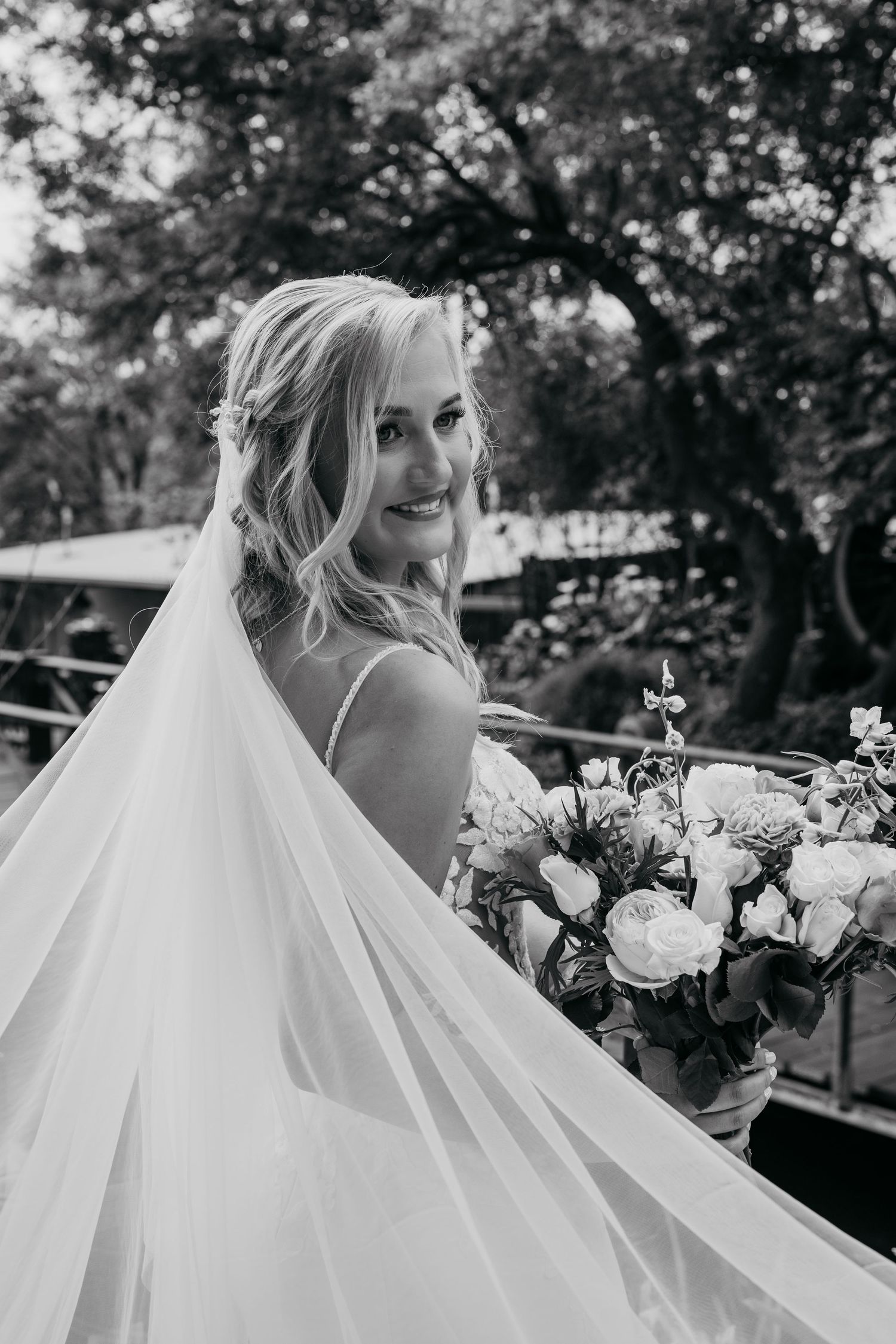 A bride in a flowing white wedding dress poses with a bouquet in a series of black and white outdoor portraits.