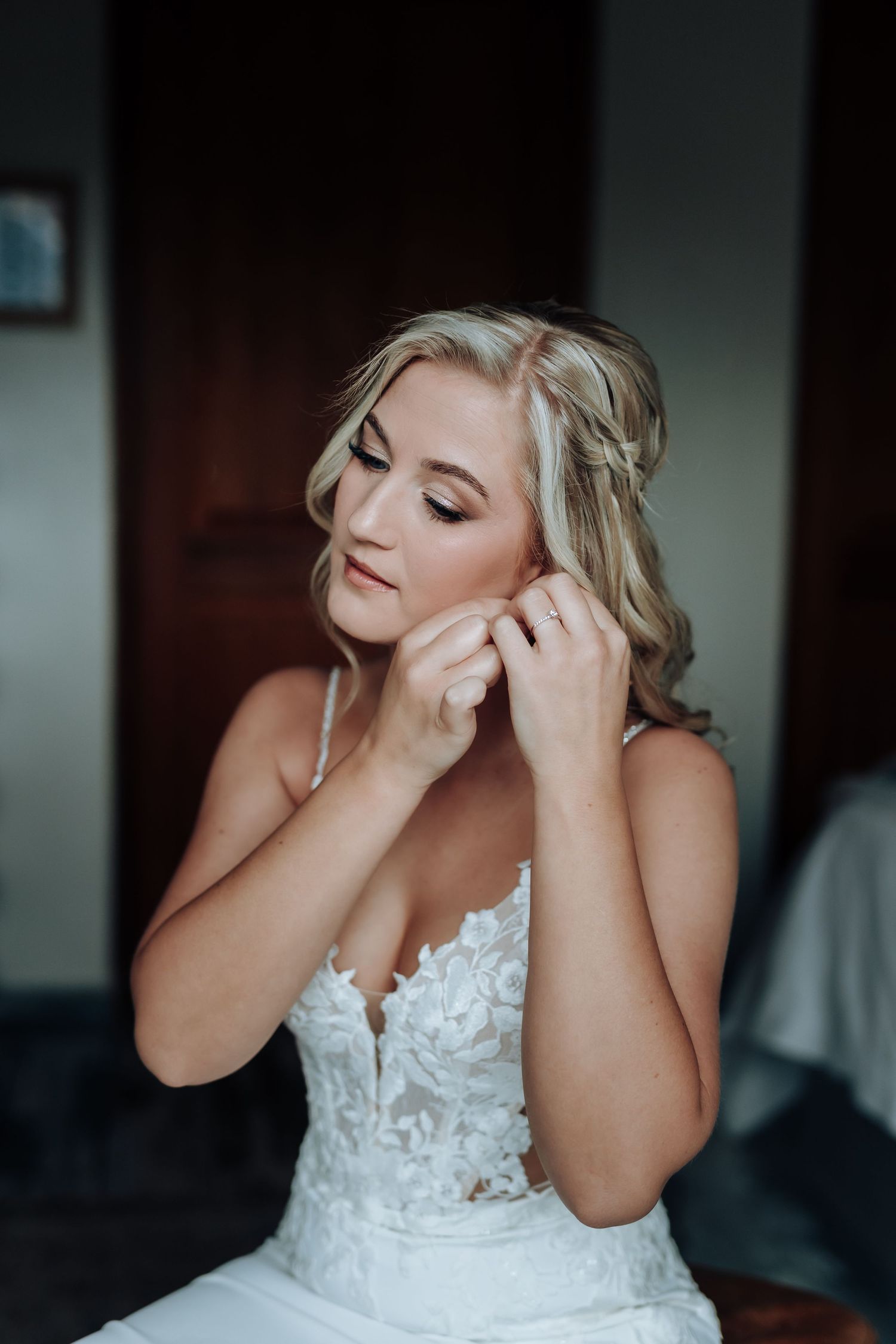 An emotional bride in a white lace wedding dress wipes tears from her eyes during a touching moment.