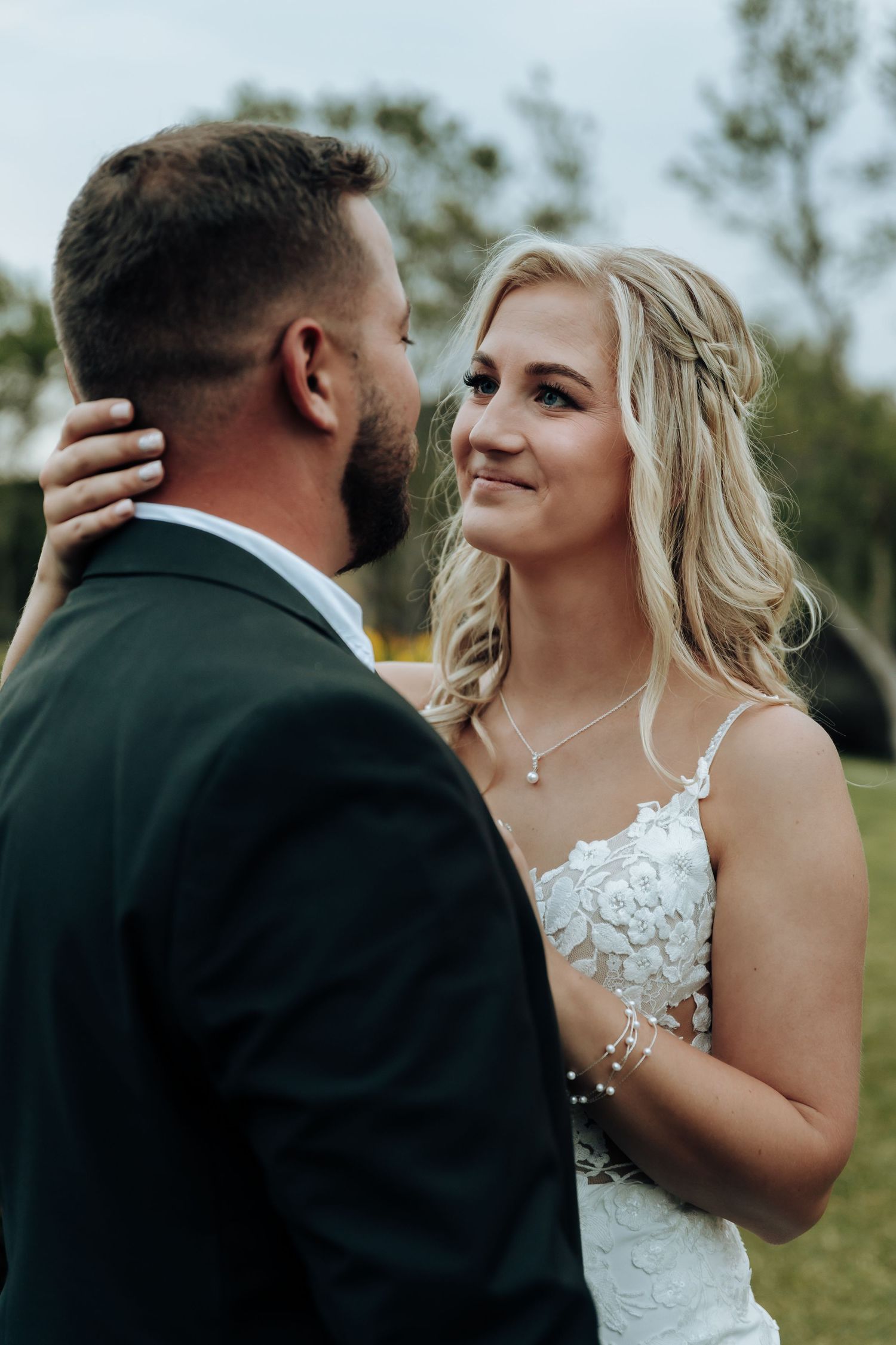 A sequence of wedding photos showing a tender first look moment between a couple in formal attire outdoors.