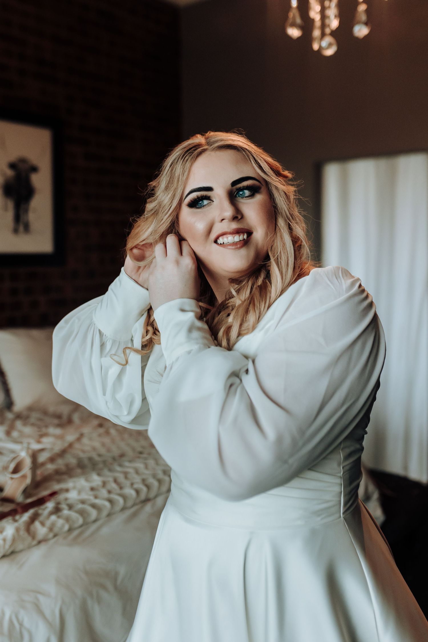 A joyful moment captured in a white dress with elegant makeup and styled blonde waves.