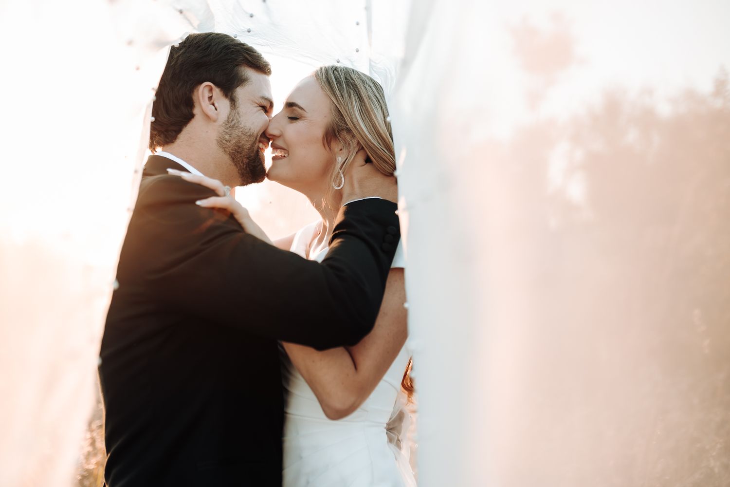 Tender moment between bride and groom embracing during their outdoor wedding photoshoot.